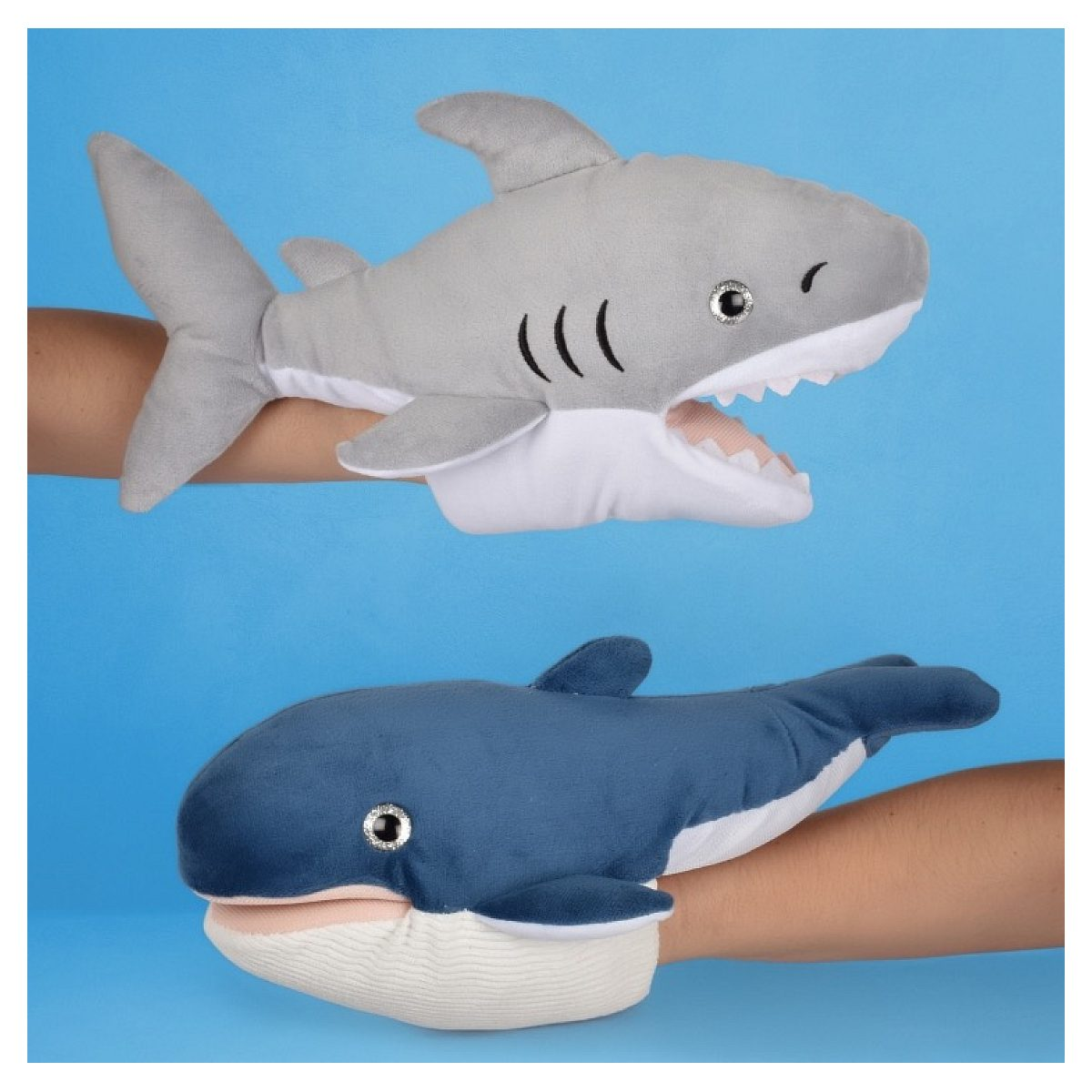 Deux mains tiennent des marionnettes en peluche, un requin gris en haut et une baleine bleue en bas, sur fond bleu.