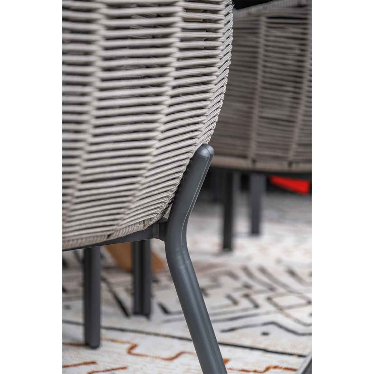 Close-up of a gray woven rope chair back with metal legs on a patterned rug.