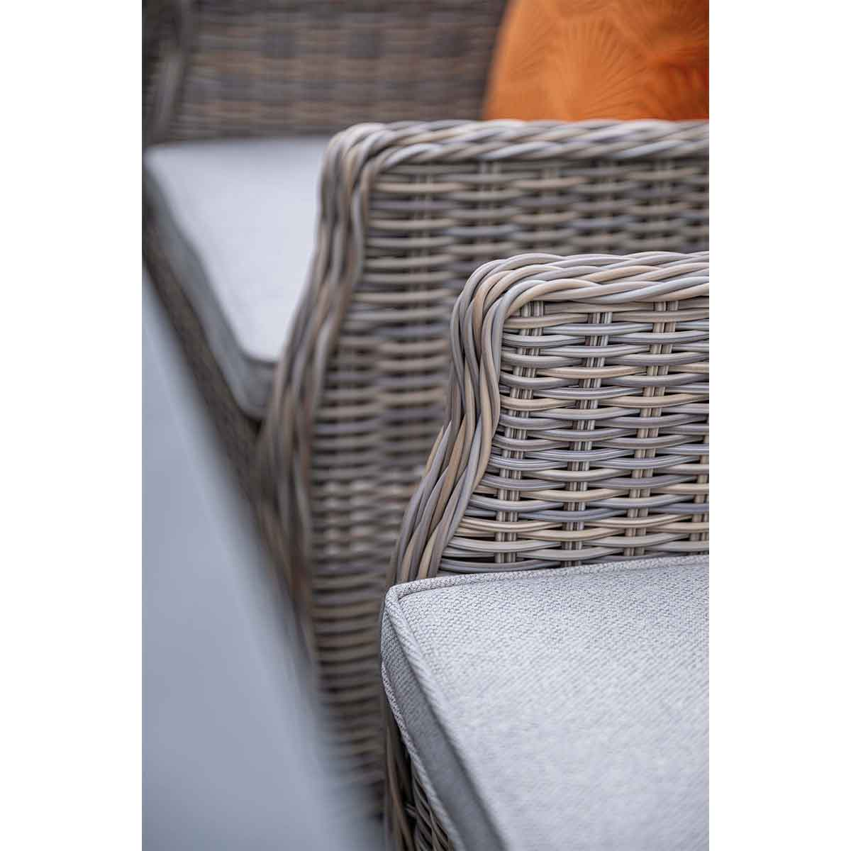 Close-up of grey rattan armchair with cushion.