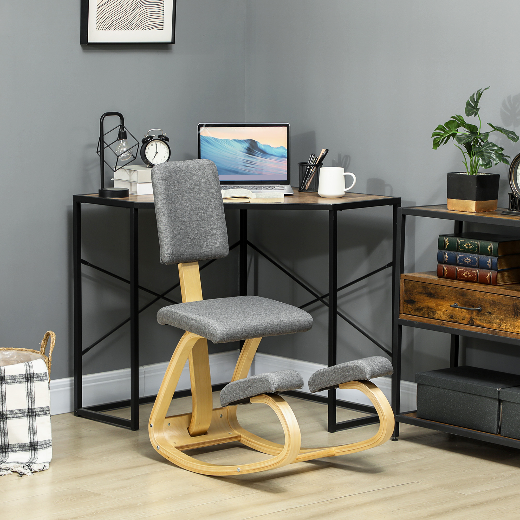 Una sedia ergonomica per ginocchia con cuscini grigi e struttura in legno si trova davanti a una scrivania.