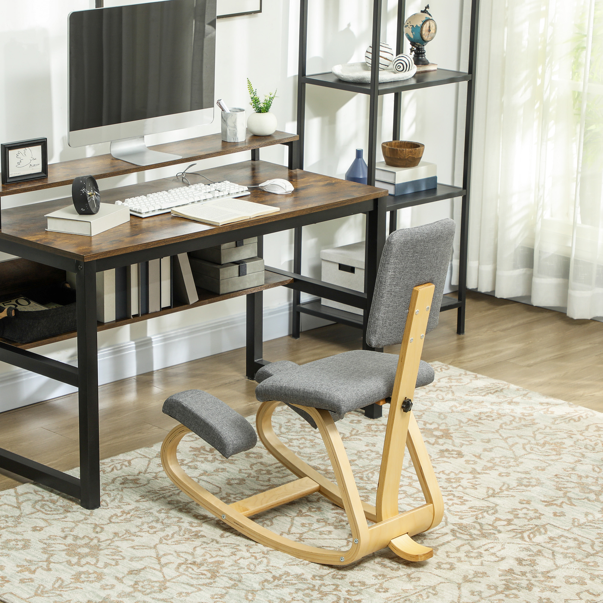 Sedia ergonomica per ginocchia con telaio in legno e cuscini grigi davanti a una scrivania.