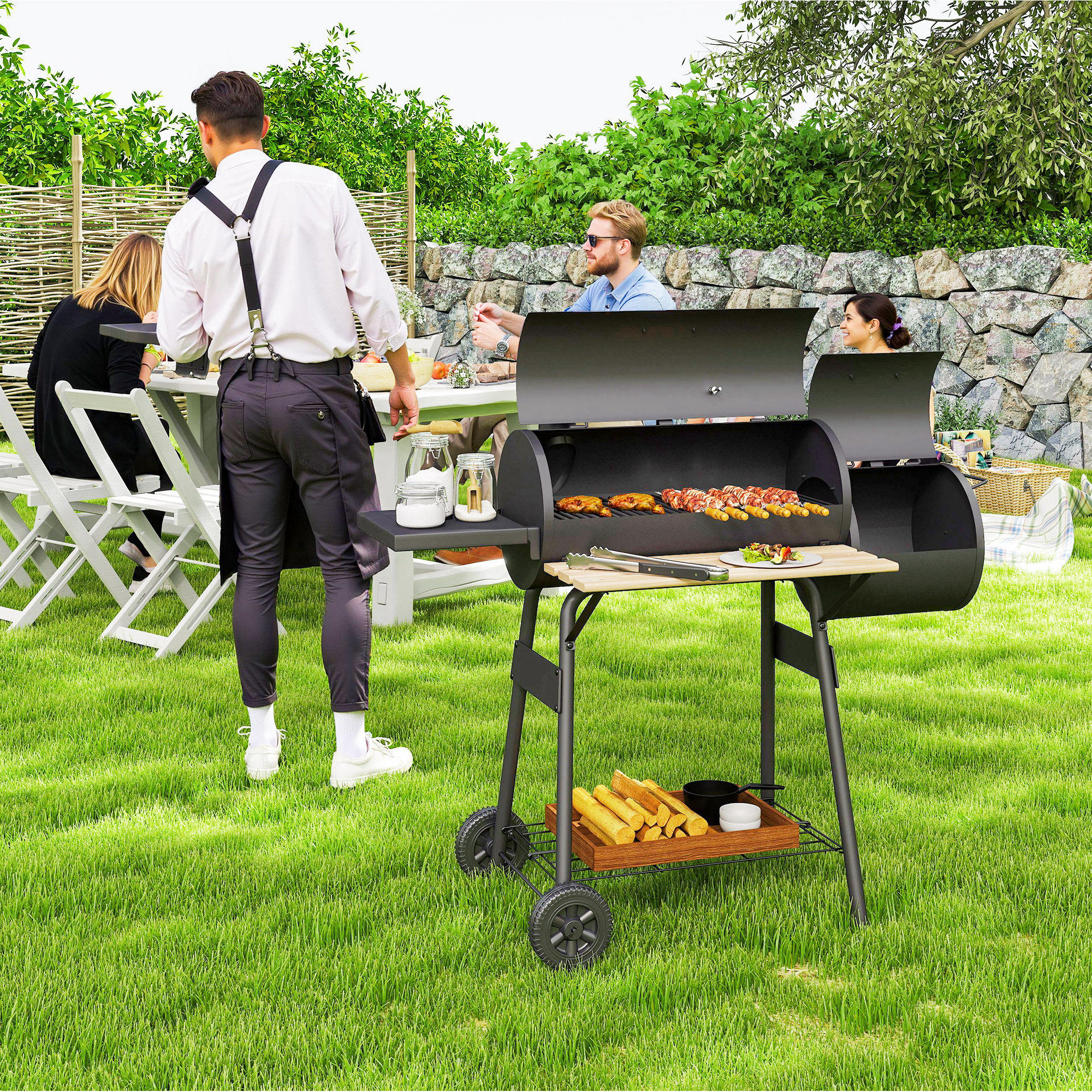 Un uomo si trova vicino a un grande barbecue nero in giardino mentre gli ospiti siedono a un tavolo.