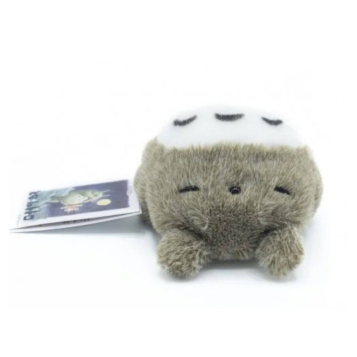 Ein flauschiges grau-weißes Totoro-Plüschtier mit angebrachtem Etikett auf weißem Hintergrund.