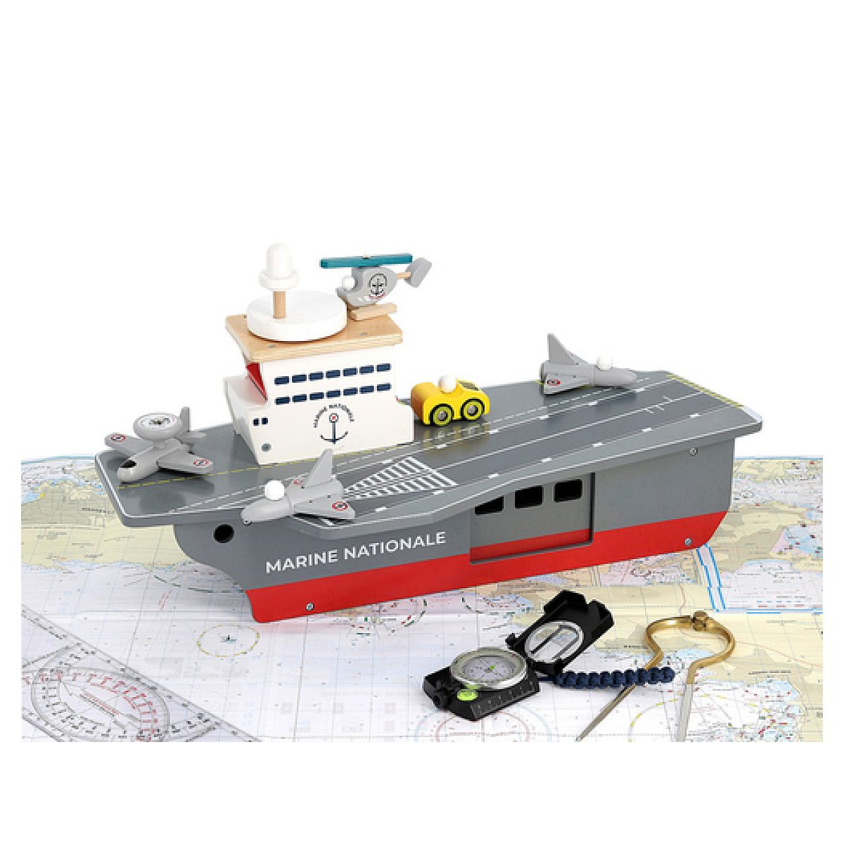 Ein hölzernes Marineschiff-Spielzeug mit Flugzeugen und Hubschrauber auf einer Weltkarte, daneben ein Kompass und ein Zirkel.