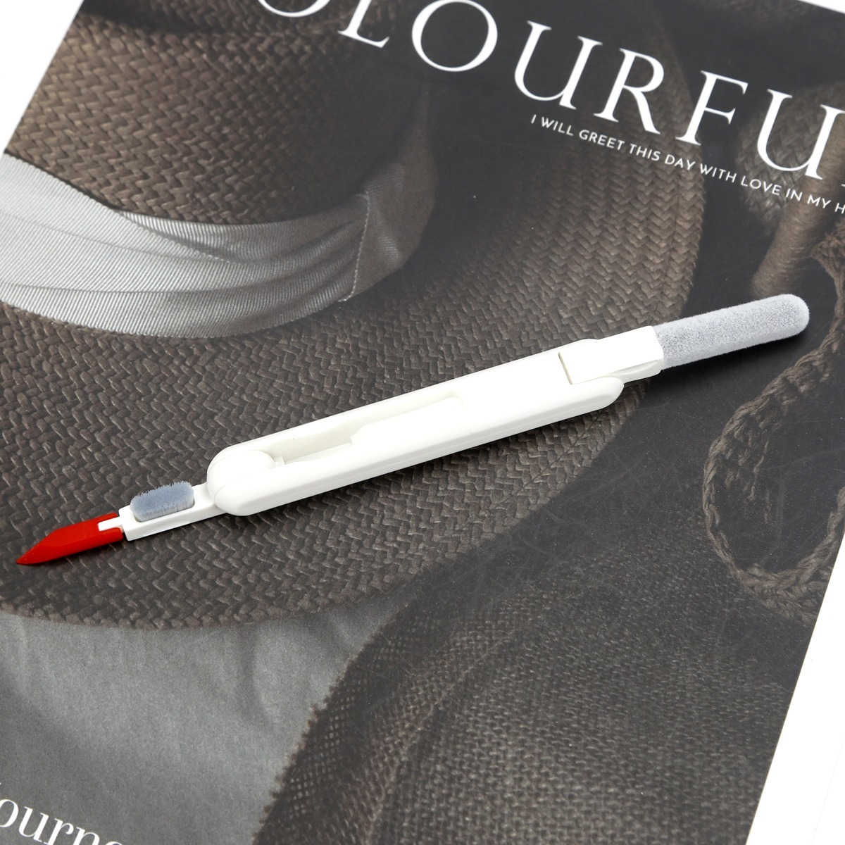 Ein weißer Reinigungsstift mit roter Spitze liegt auf einer strukturierten Oberfläche.