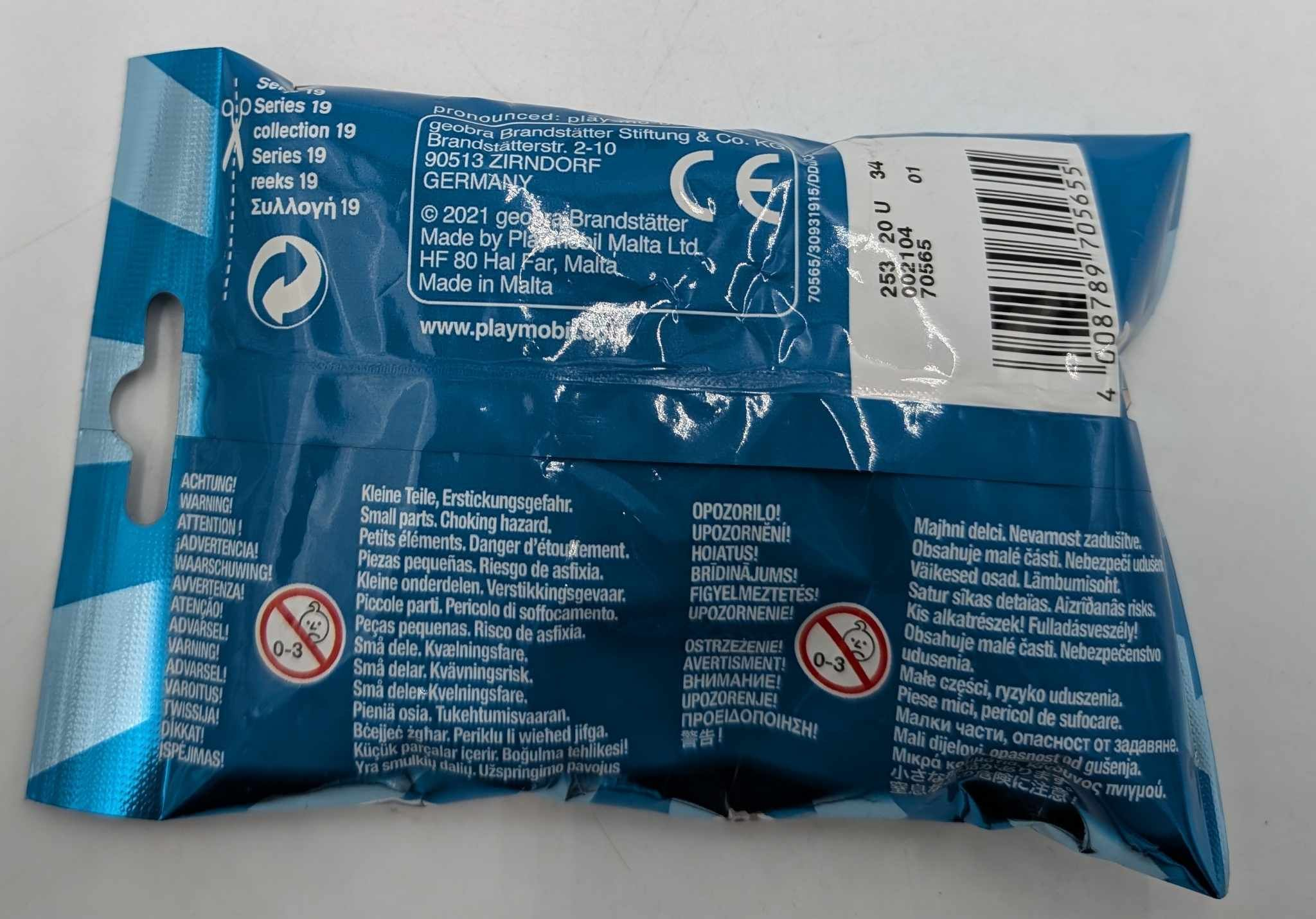 Parte posterior de un paquete sorpresa azul de Playmobil con marca CE, código de barras y advertencias.