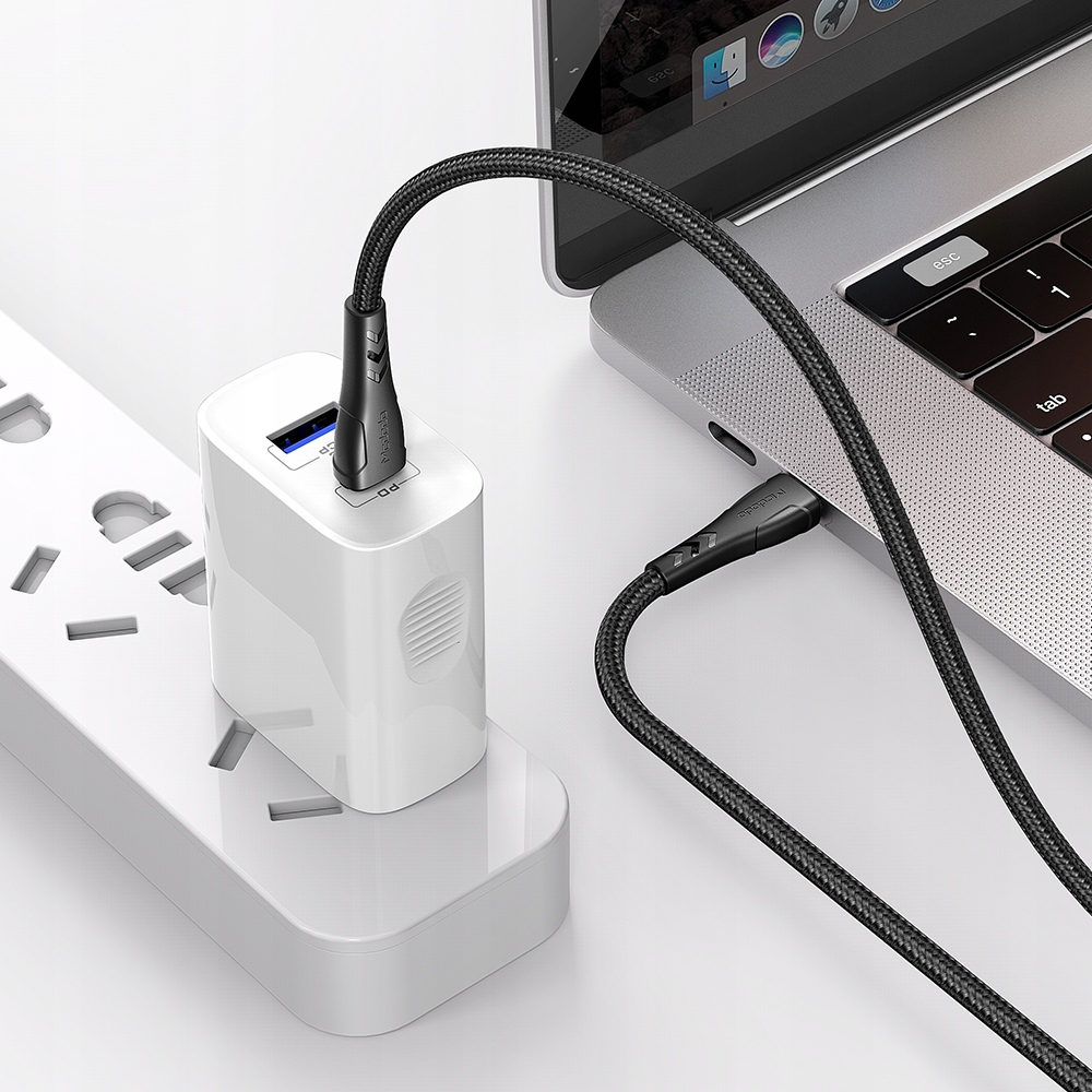 Un caricatore USB bianco inserito in una ciabatta e collegato a un computer portatile con un cavo nero.