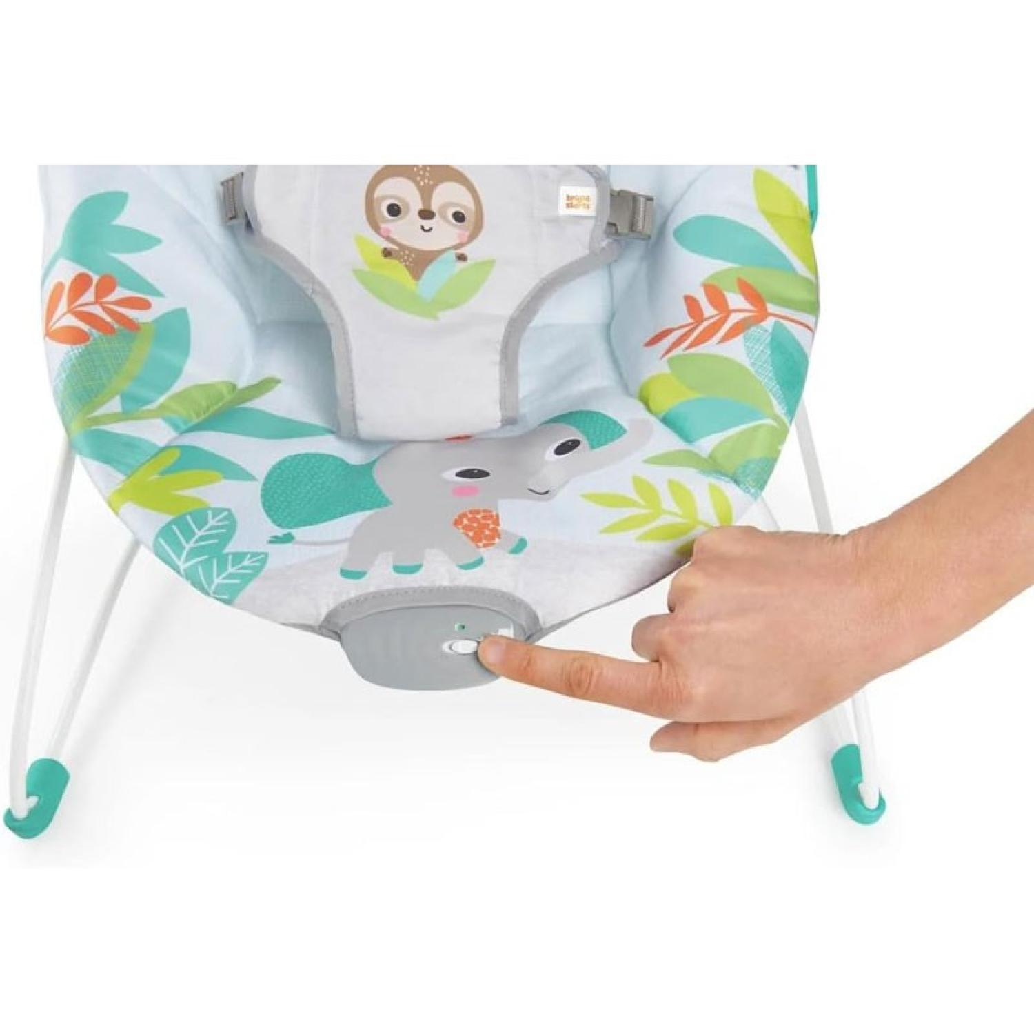 Eine Hand schaltet eine graue Babyschaukel mit Dschungelmotiv ein.
