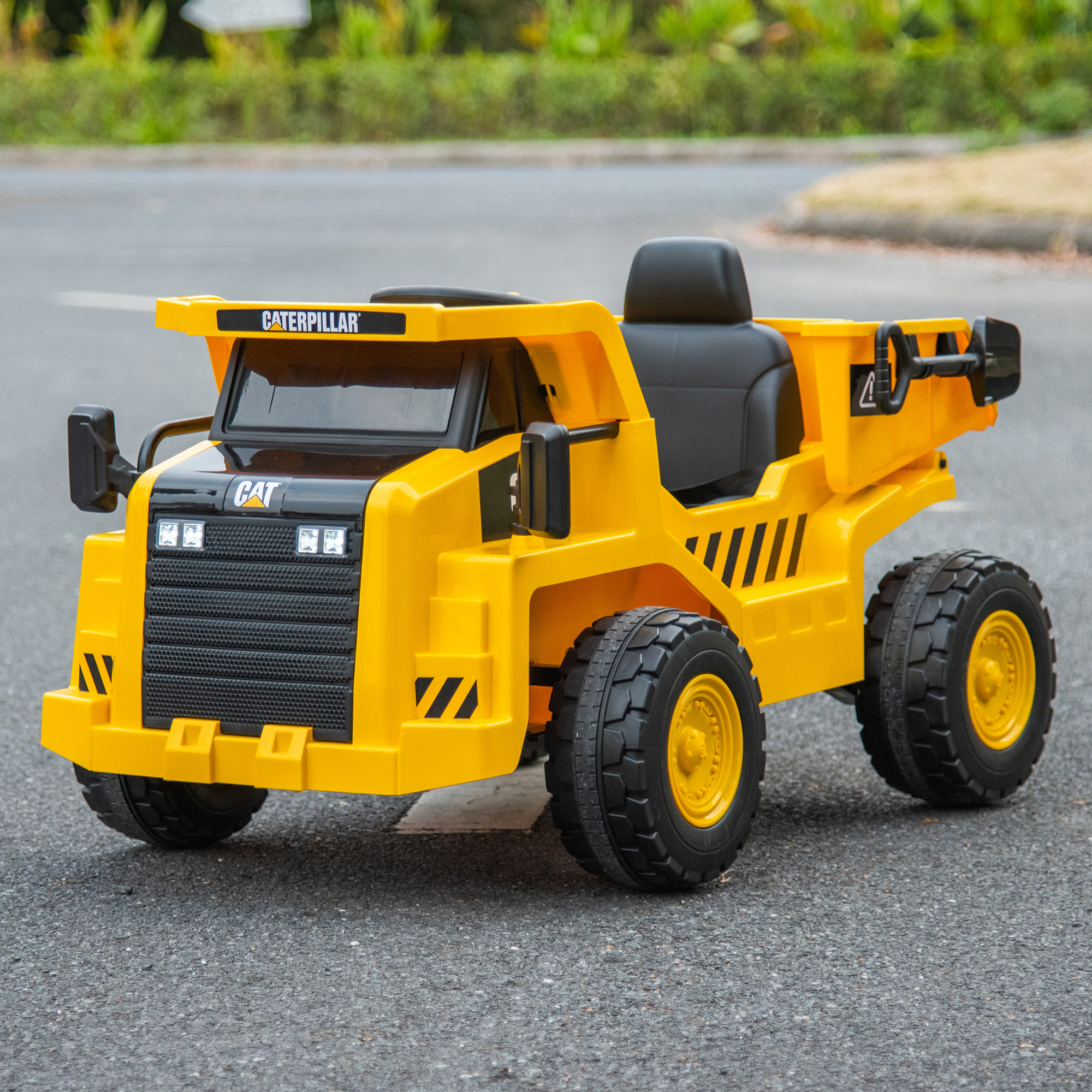 Un camion dumper giocattolo Caterpillar giallo e nero parcheggiato sull'asfalto.
