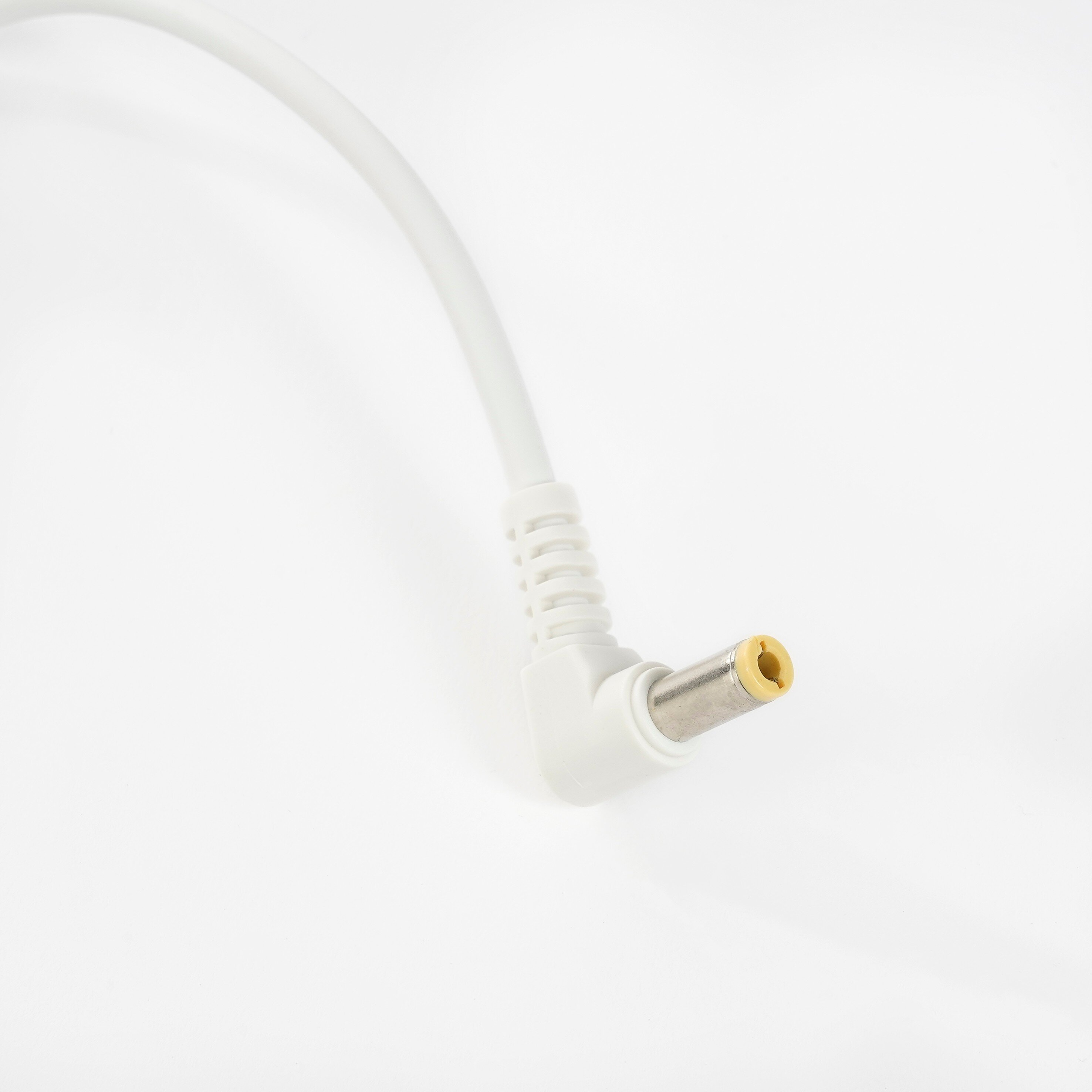 Ein weißes Stromkabel mit einem abgewinkelten DC-Stecker auf weißem Hintergrund.