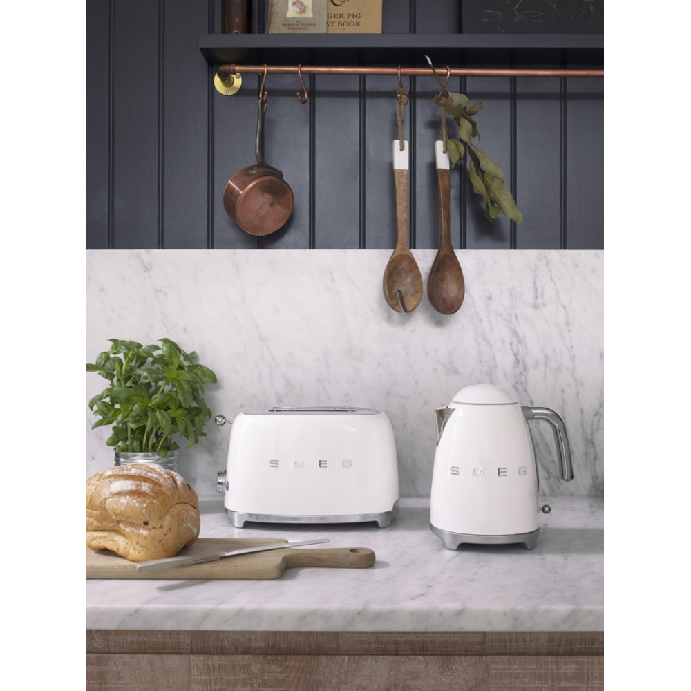 Eine weiße SMEG-Toaster und ein Wasserkocher auf einer Marmorarbeitsplatte, mit Brot und Kräutern.