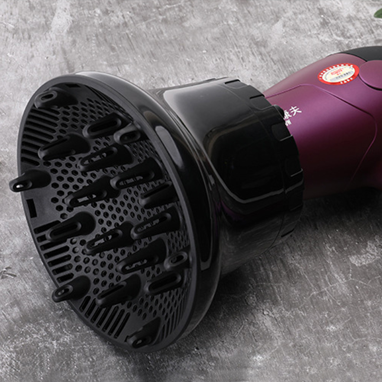 Un asciugacapelli viola con un grande diffusore nero giace su una superficie grigia.