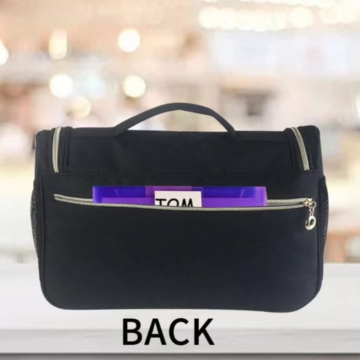 Un beauty case nero da appendere visto da dietro con tasca con zip e cartelle viola. Testo in basso: "BACK".