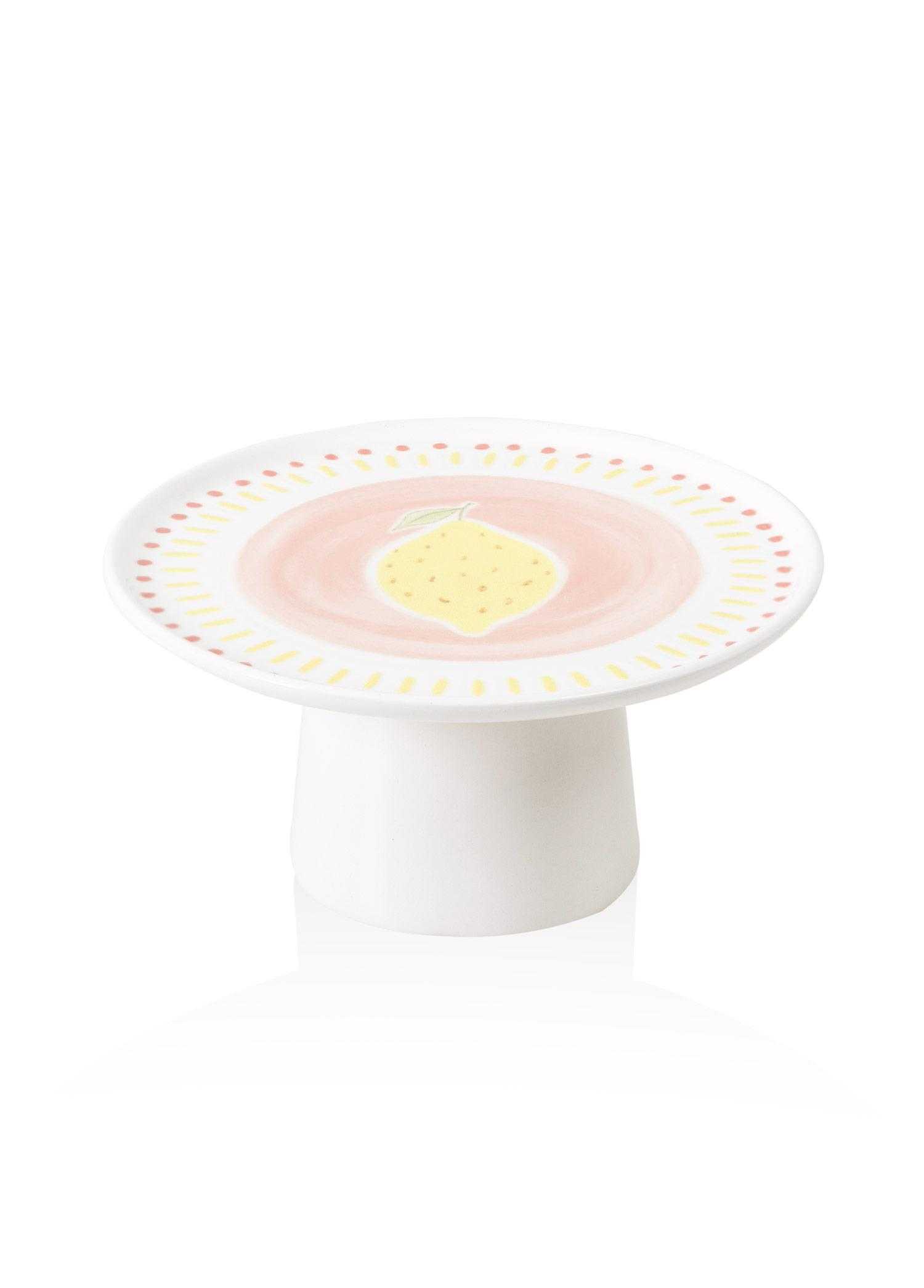 Ortasında sarı bir limon olan, pembe ve sarı desenlerle süslenmiş beyaz seramik pasta standı.
