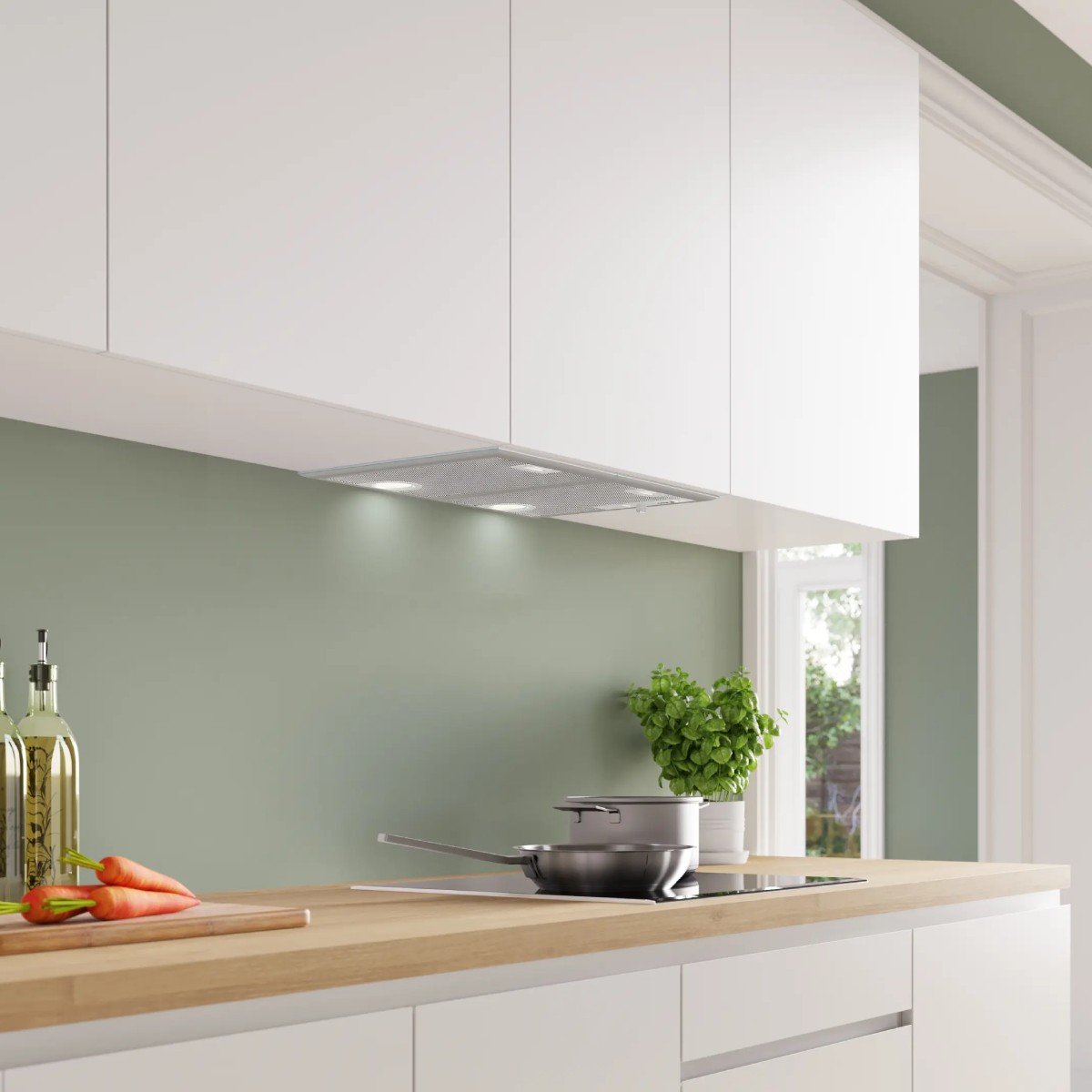Cocina moderna con gabinetes blancos, encimera de madera, campana extractora, olla, sartén y zanahorias.