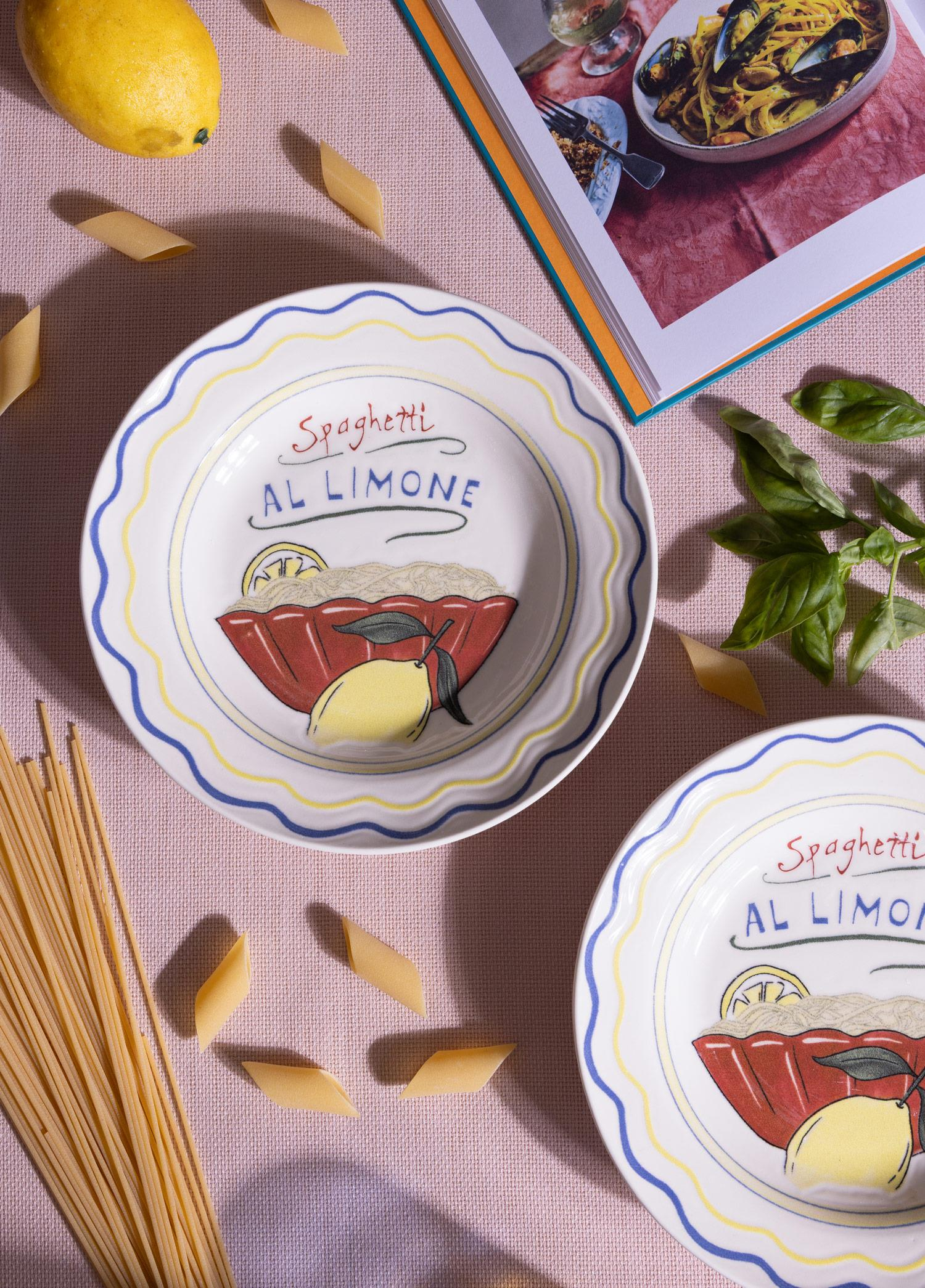 Pembe kumaş üzerinde Spaghetti Al Limone tabaklar, limon, penne, spagetti, fesleğen ve yemek kitabı.