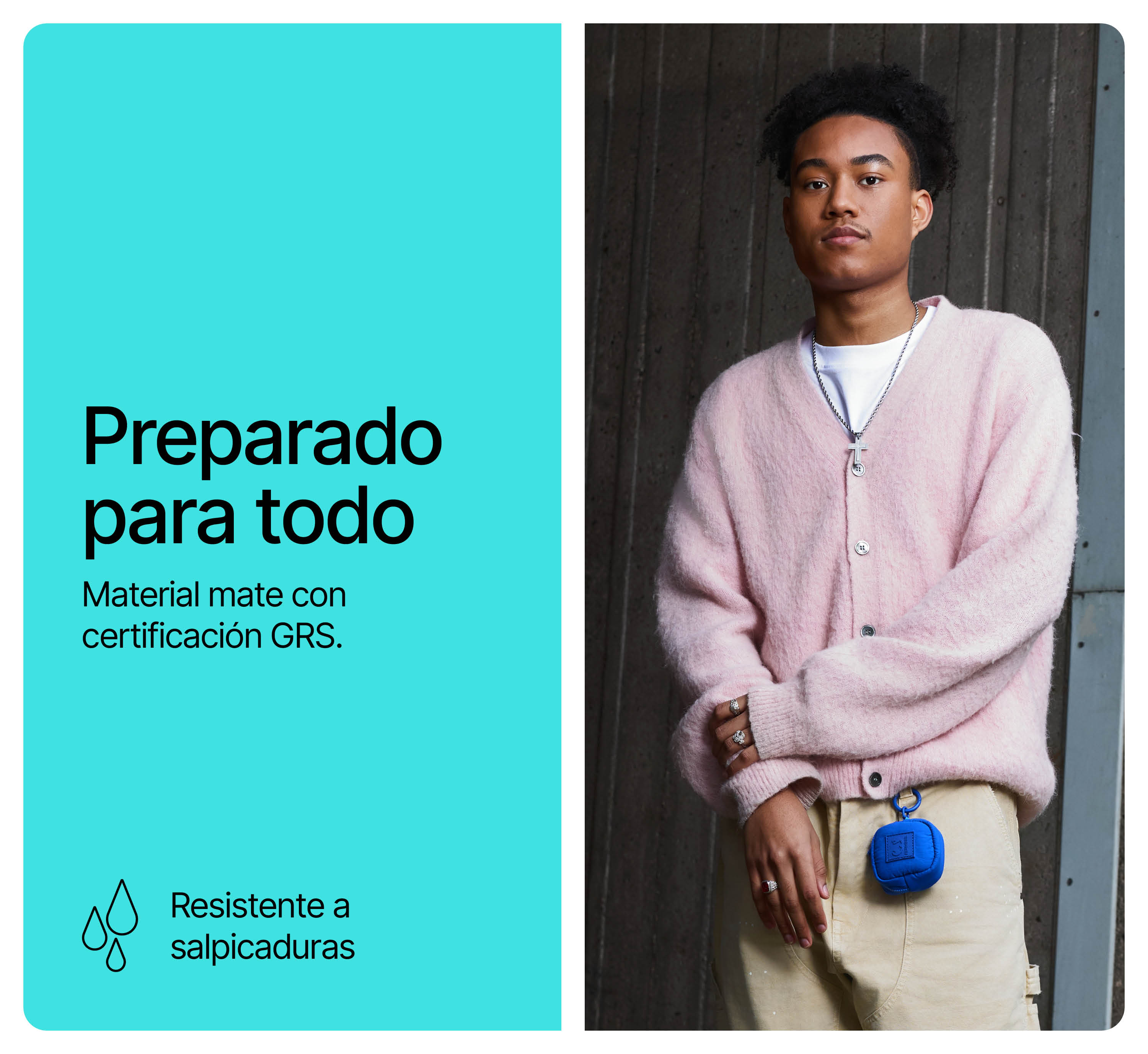 Un joven con un cárdigan rosa y pantalones beis está de pie ante un muro de hormigón gris.