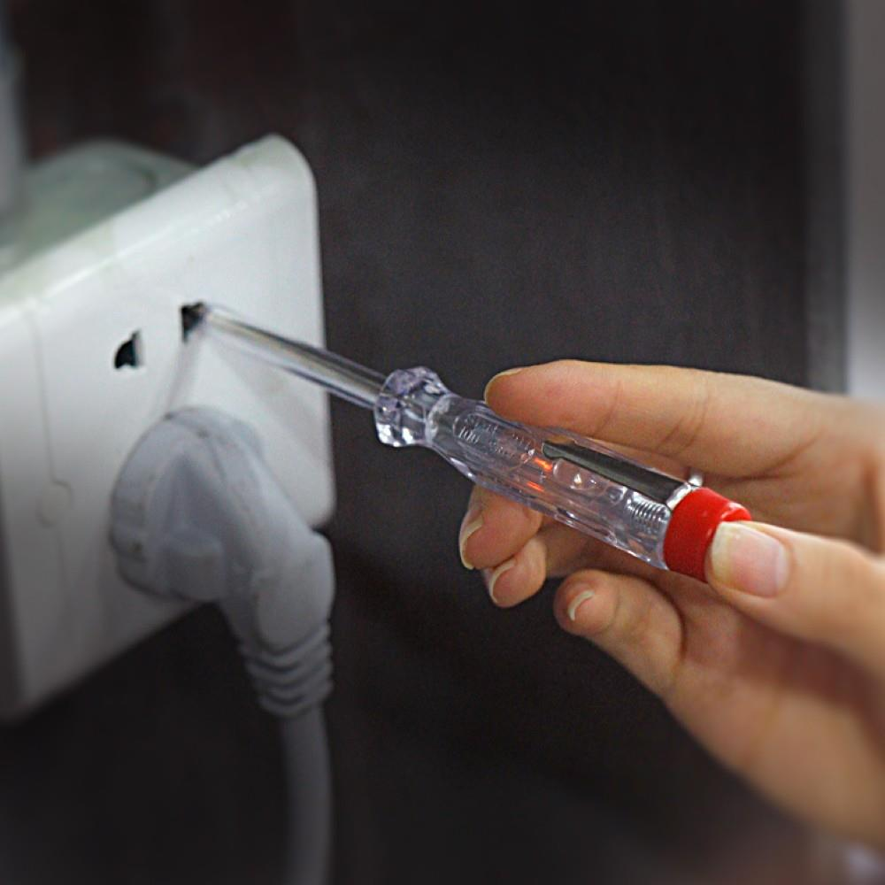 Bir el, duvardaki prizde voltaj test cihazı kullanıyor.