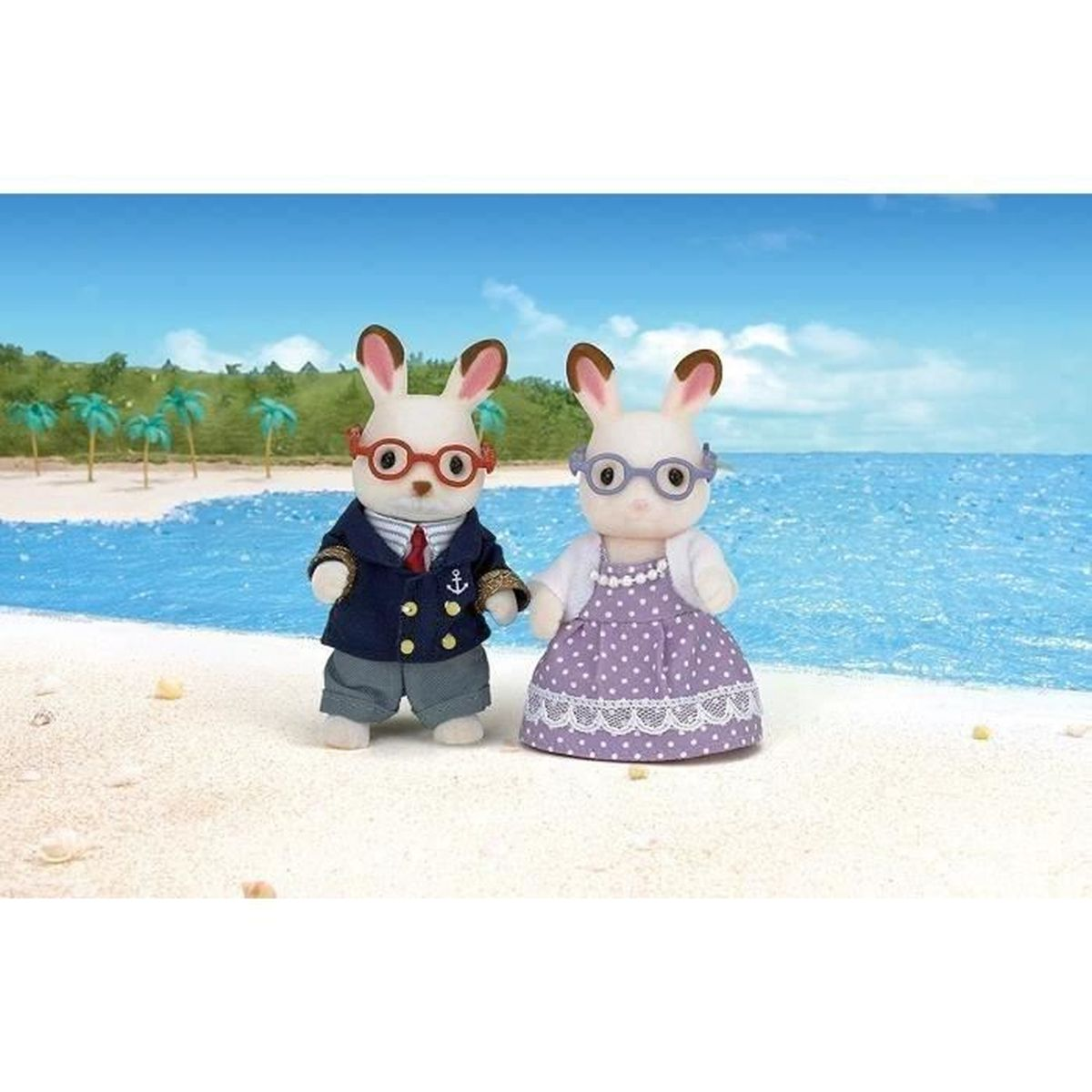 Zwei Plüschhasenfiguren in Outfits stehen am Strand vor dem blauen Meer mit Palmen im Hintergrund.
