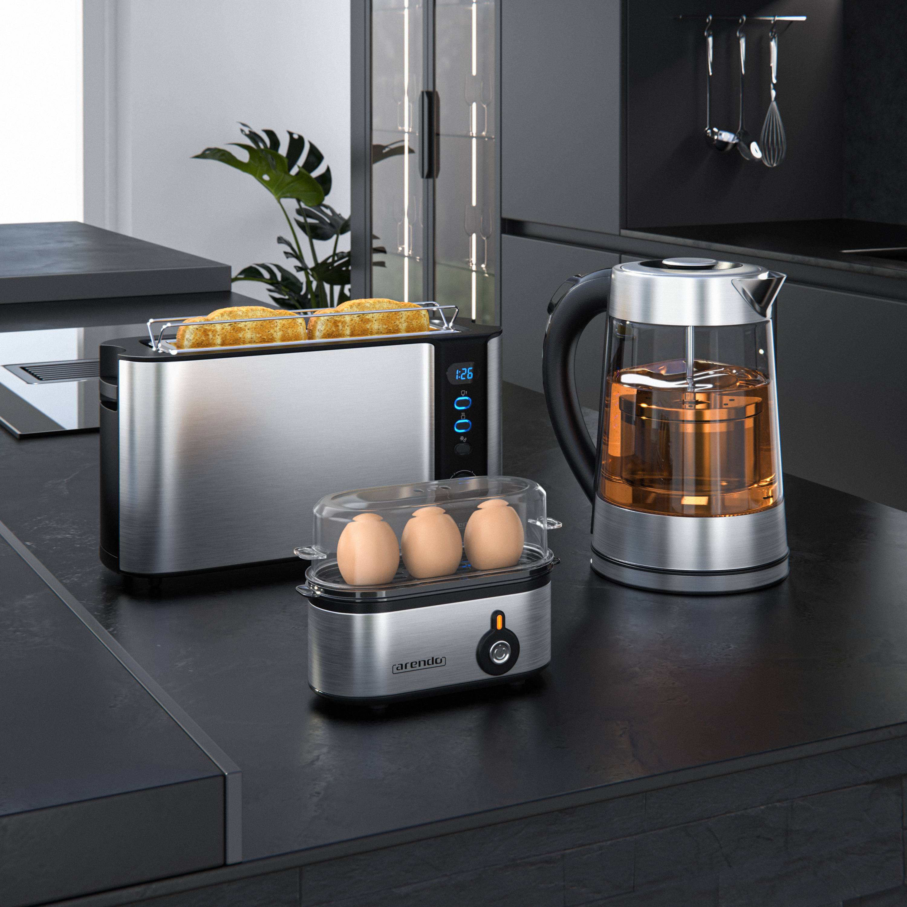 Ein Toaster, ein Eierkocher mit drei Eiern und ein Wasserkocher auf einer schwarzen Küchenarbeitsplatte.