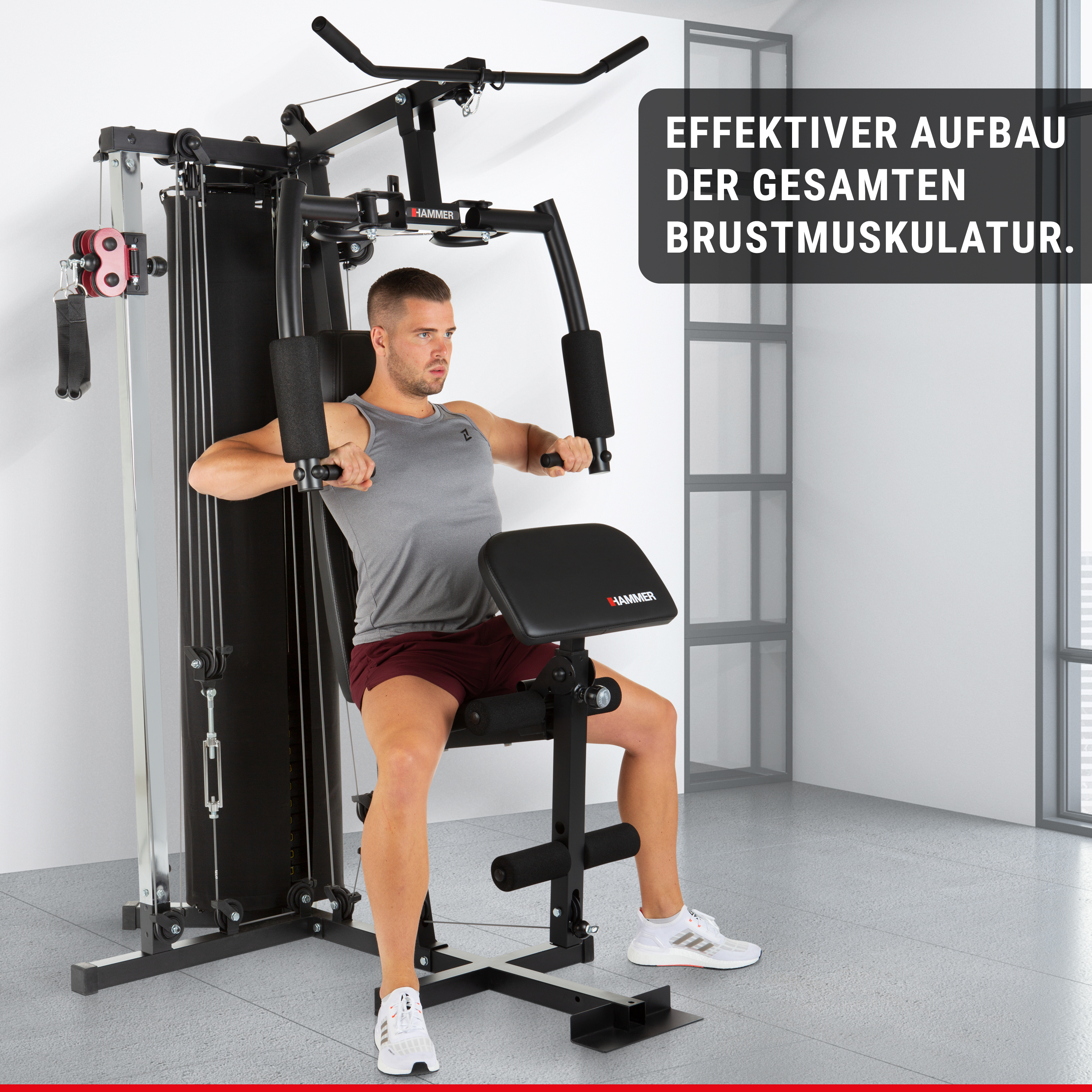 Ein Mann sitzt auf einer schwarzen Kraftstation und trainiert seine Brustmuskulatur in einem hellen Raum.