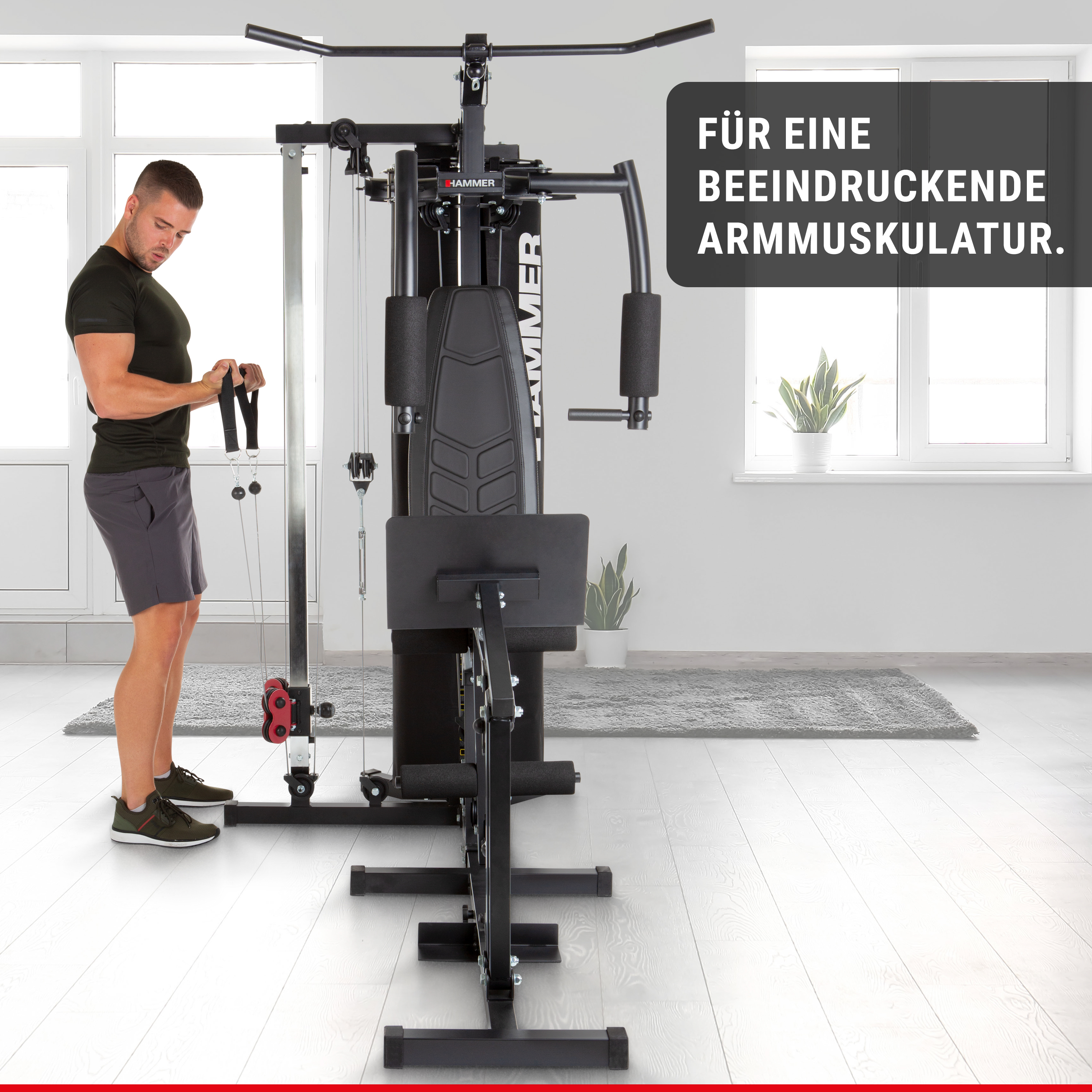 Ein Mann im Fitnessshirt trainiert an einer schwarzen Kraftstation in einem hellen Raum.