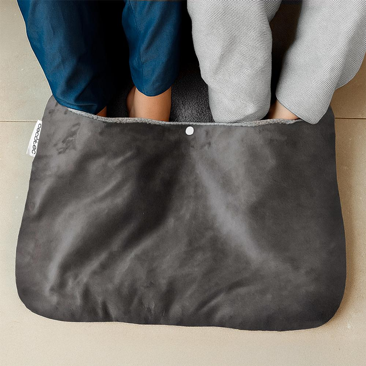 Due persone scaldano i piedi insieme dentro uno scaldapiedi elettrico grigio.
