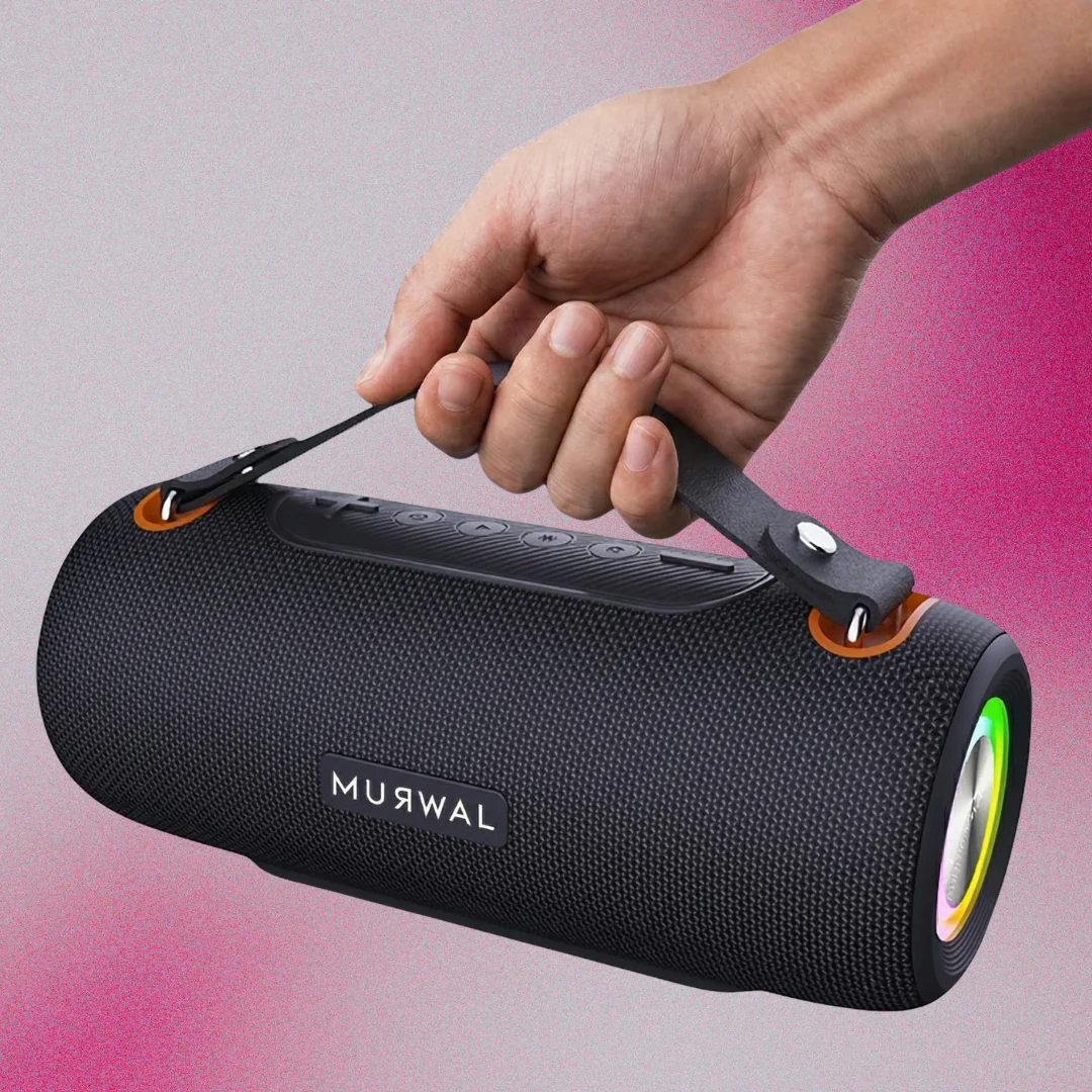 Una mano sostiene un altavoz bluetooth negro portátil con luces coloridas en los extremos sobre un fondo rosa.