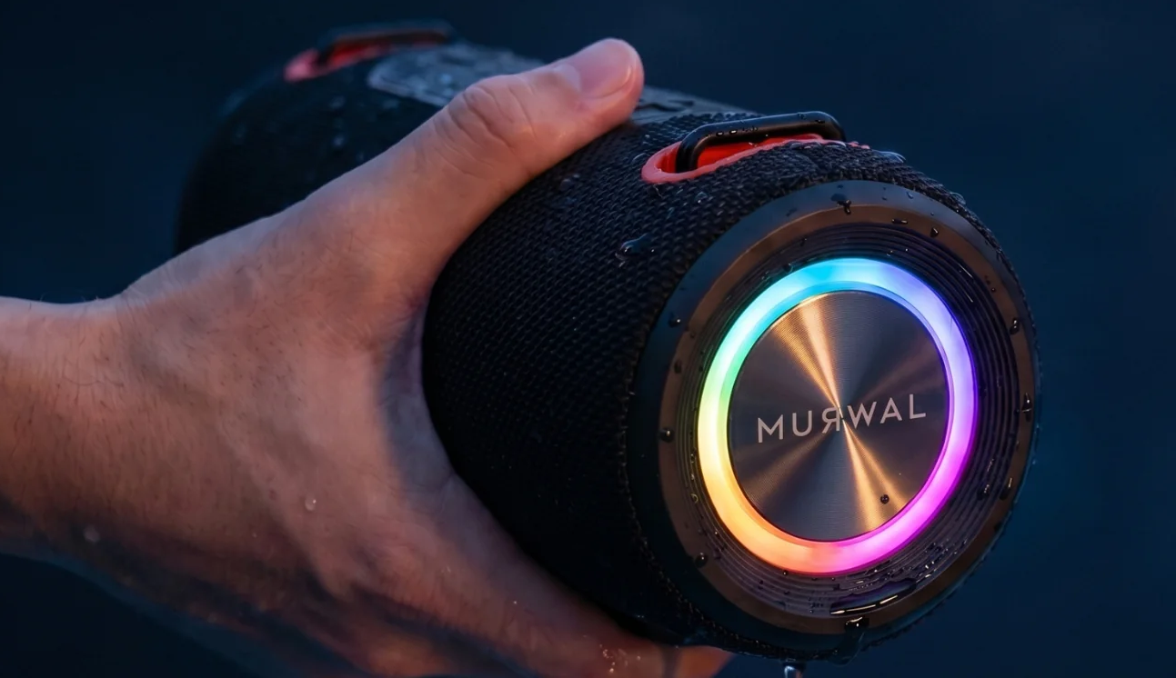 Una mano sostiene un altavoz Bluetooth negro e impermeable con un anillo LED multicolor.