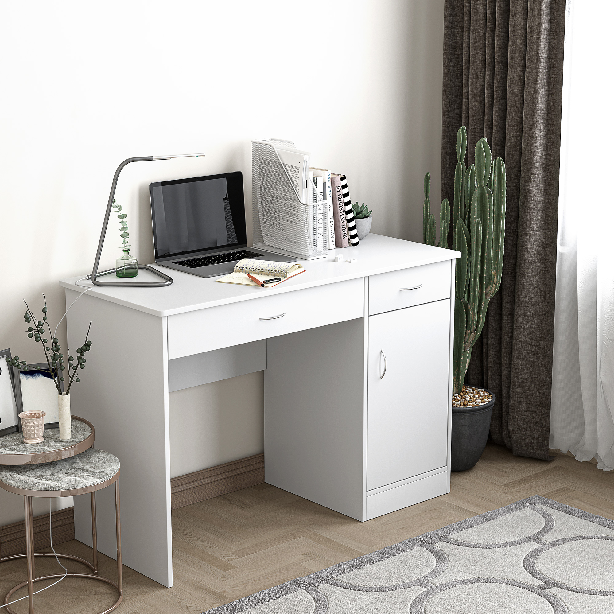 Una scrivania bianca con laptop, lampada e libri, accanto a un cactus in vaso e tende grigie.