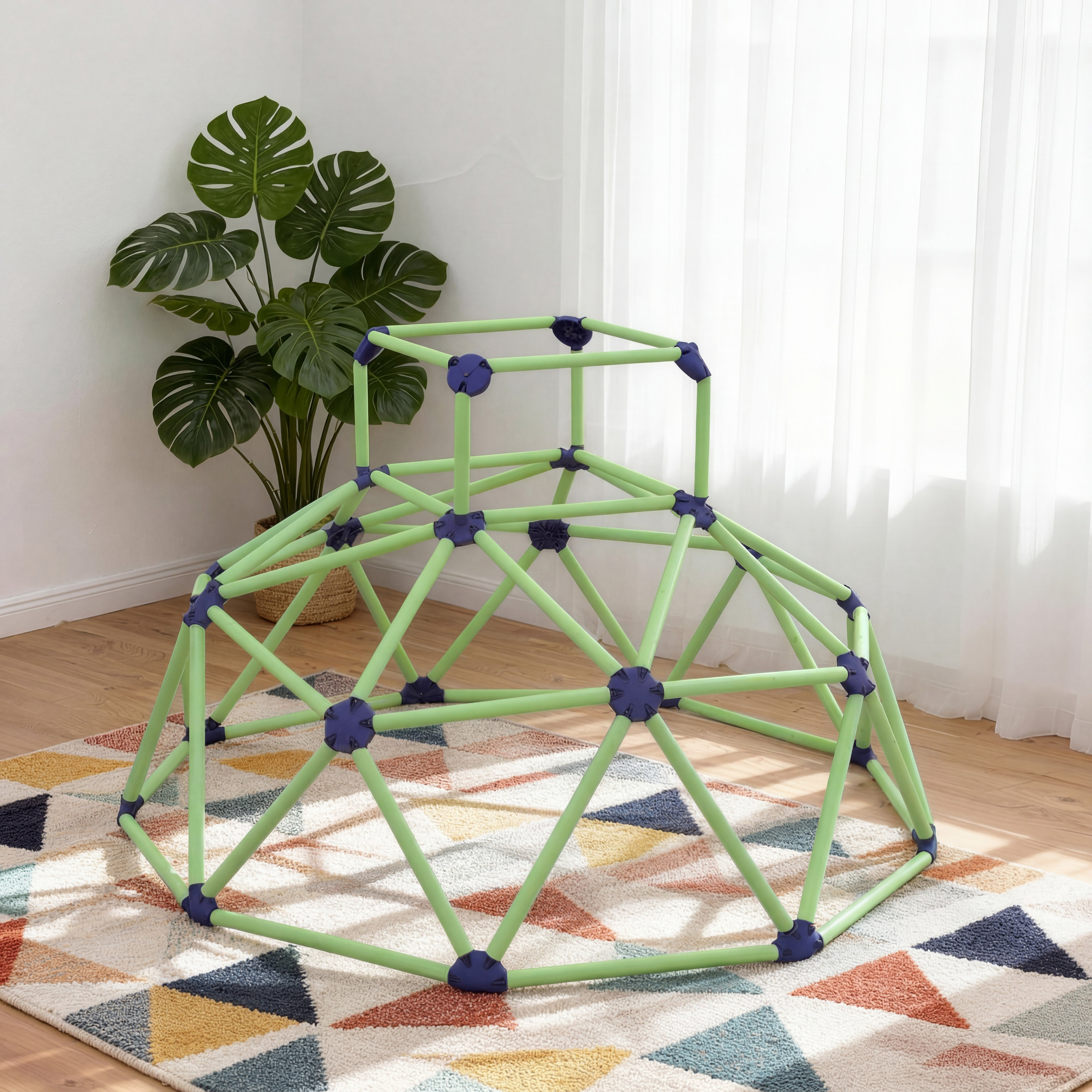 Una cupola da arrampicata verde con connettori blu su un tappeto geometrico vicino a una pianta in vaso.
