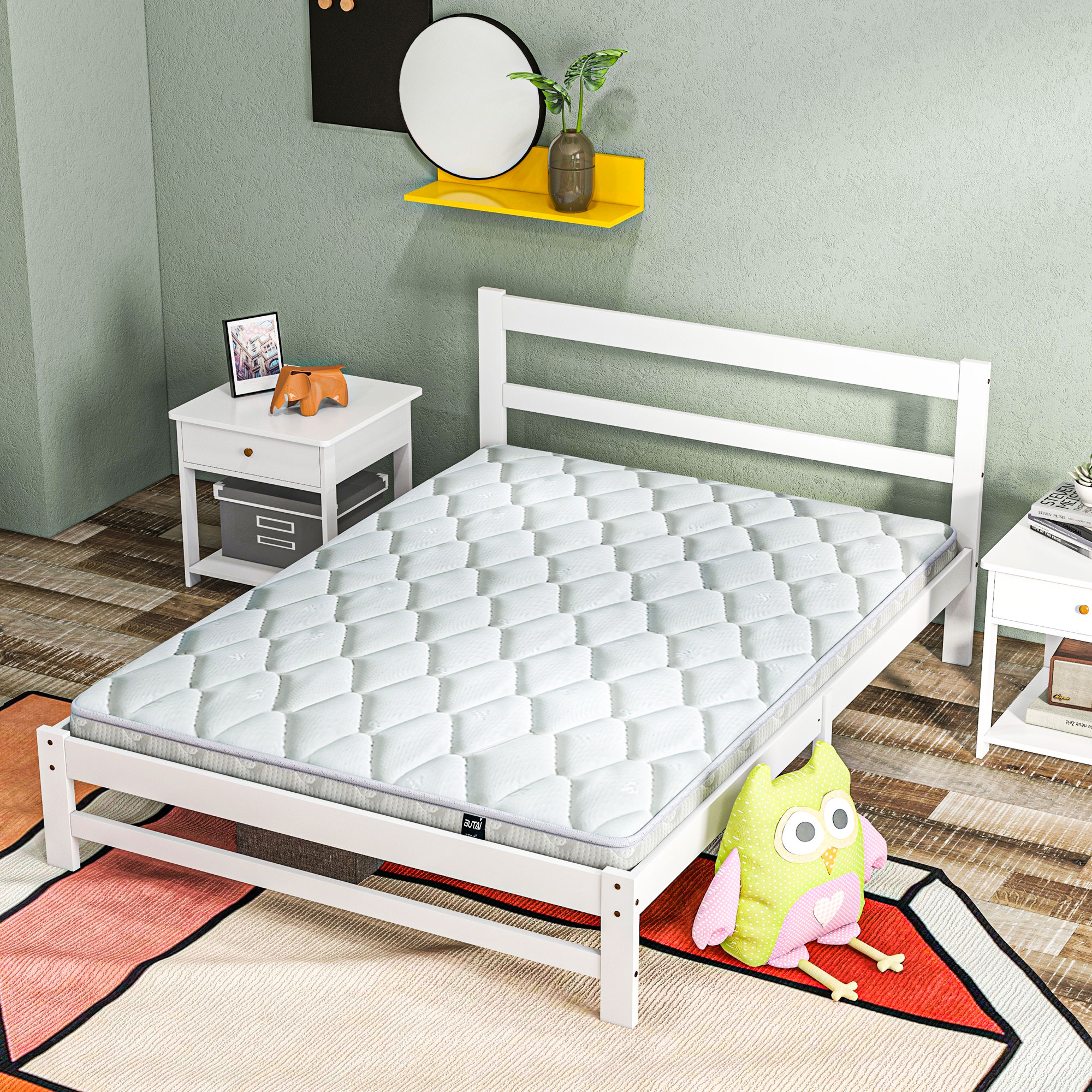 Una cama de madera blanca con colchón sobre una alfombra colorida, flanqueada por dos mesitas de noche y pared verde.