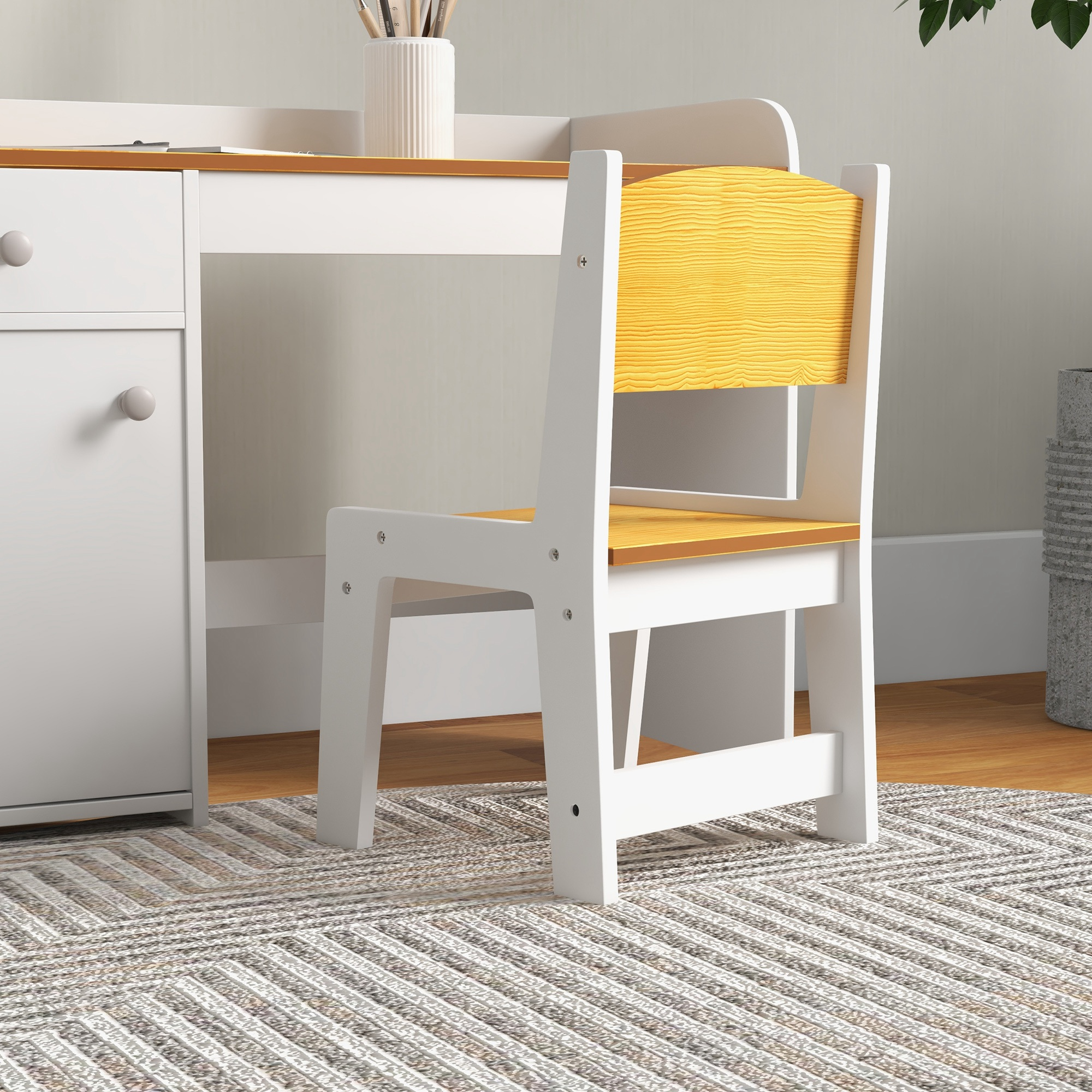 Un escritorio infantil blanco y de madera con su silla a juego sobre una alfombra en una habitación luminosa.