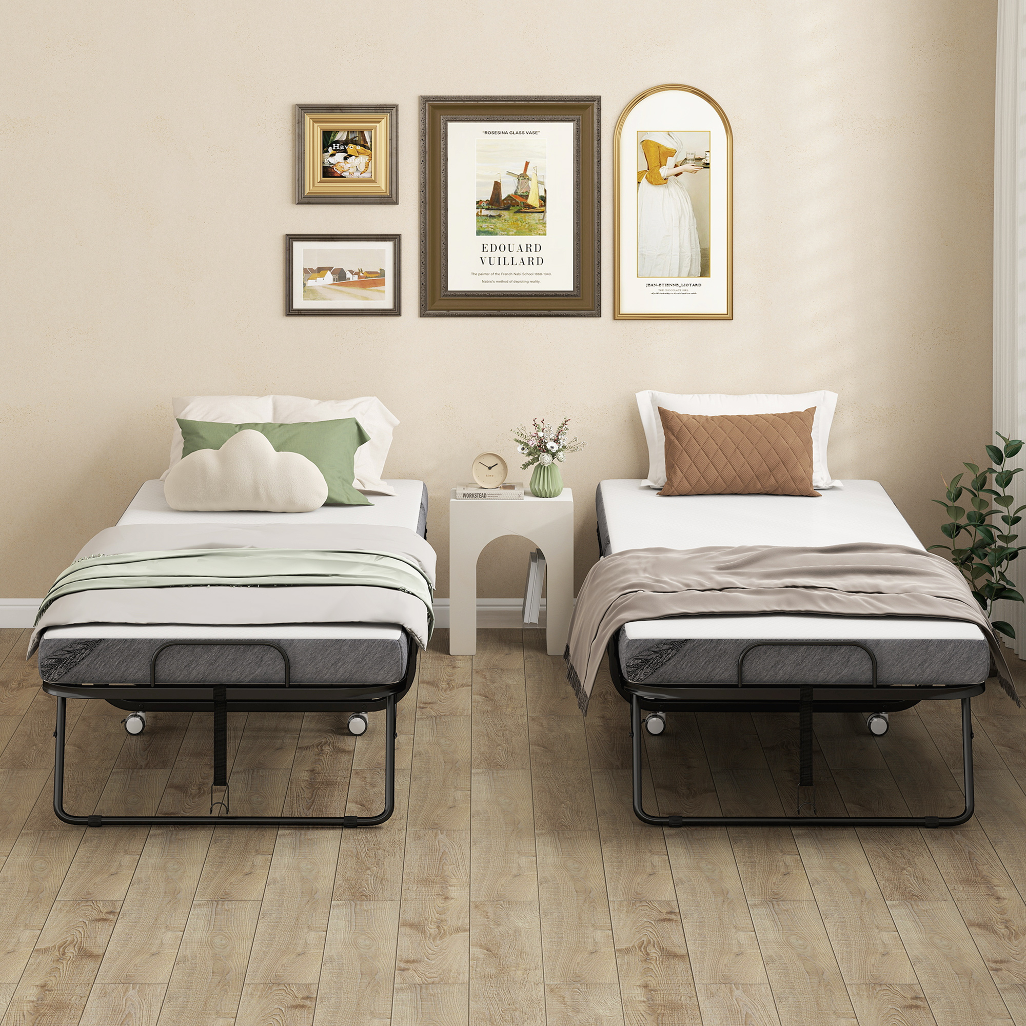 Dos camas plegables con ruedas y ropa de cama se encuentran frente a una pared beige con cuatro cuadros.
