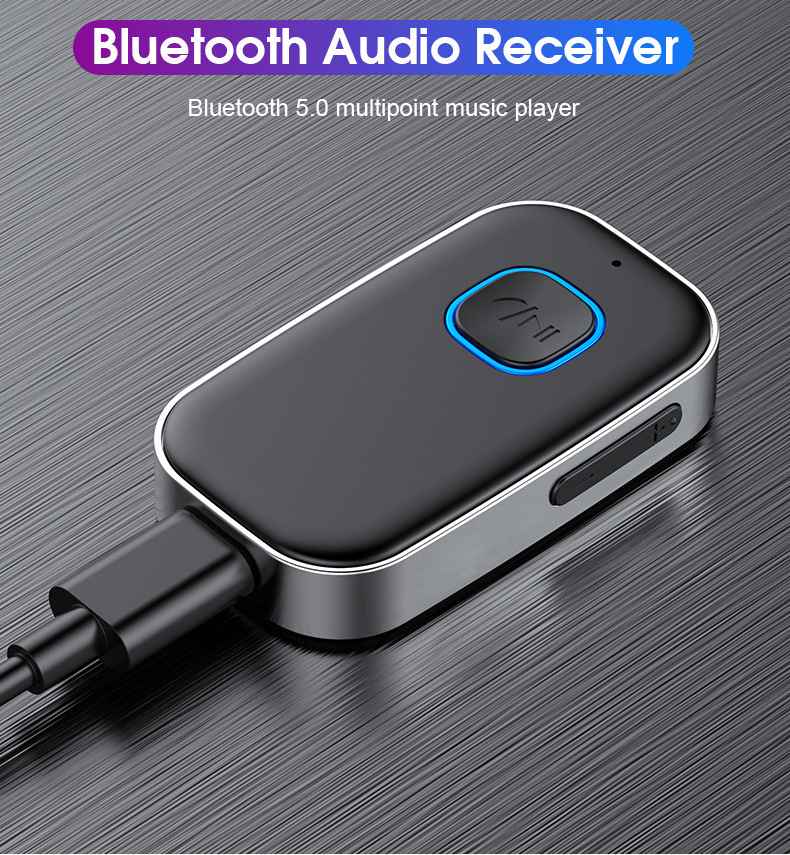 Ein schwarzer Bluetooth-Audioempfänger mit blauem Leuchtknopf und angeschlossenem Kabel auf Metallstruktur.
