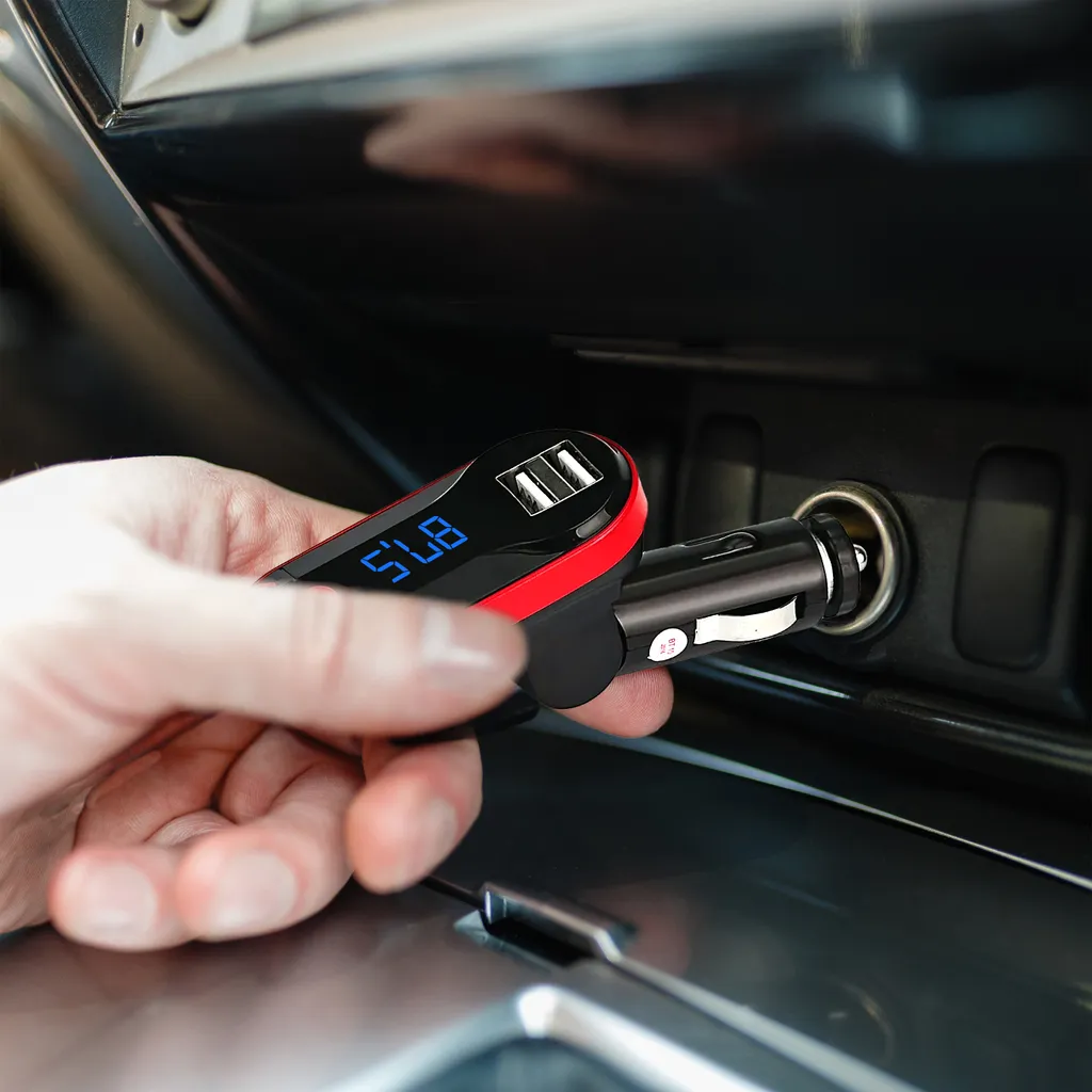 Eine Hand steckt einen FM-Transmitter mit blauer LED-Anzeige und zwei USB-Anschlüssen in den Zigarettenanzünder.