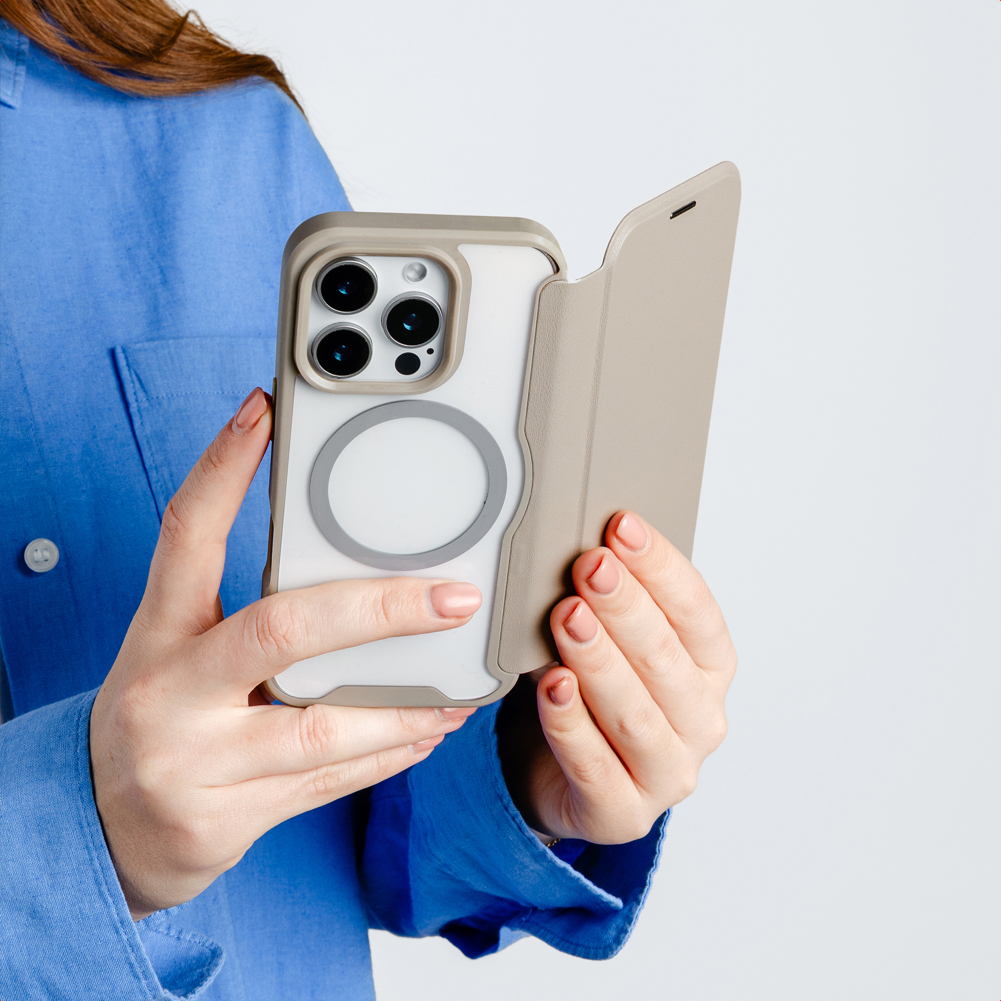 Eine Person im blauen Hemd hält ein Smartphone mit beige Klapphülle und zeigt die Rückseite mit drei Kameras.