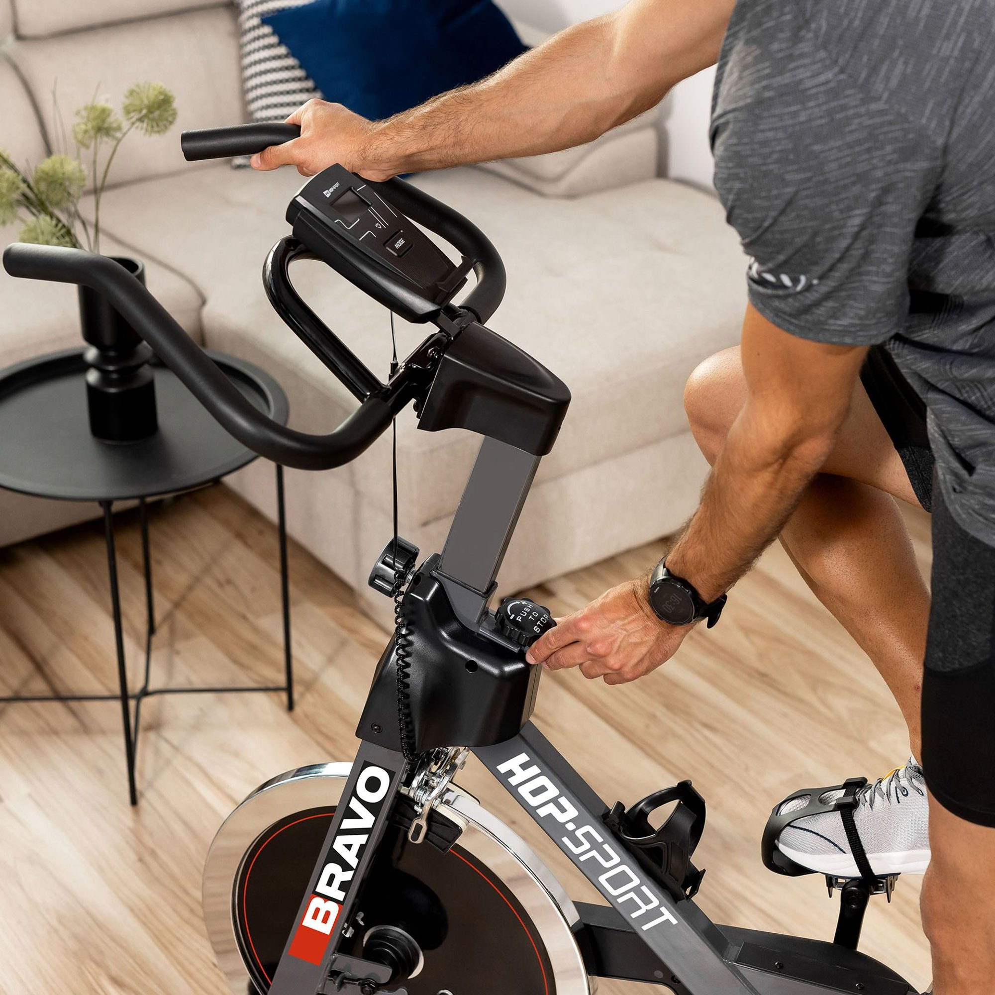 Ein Mann im grauen T-Shirt fährt drinnen auf einem Hop-Sport Bravo Ergometer.