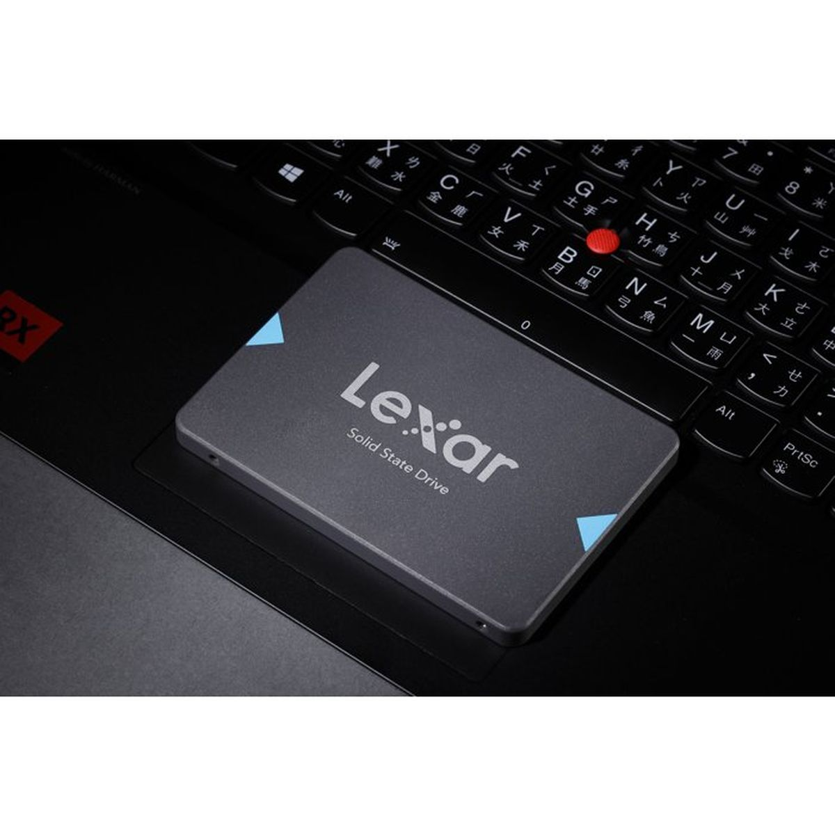 Eine graue Lexar SSD liegt auf der Tastatur und dem Trackpad eines Laptops.