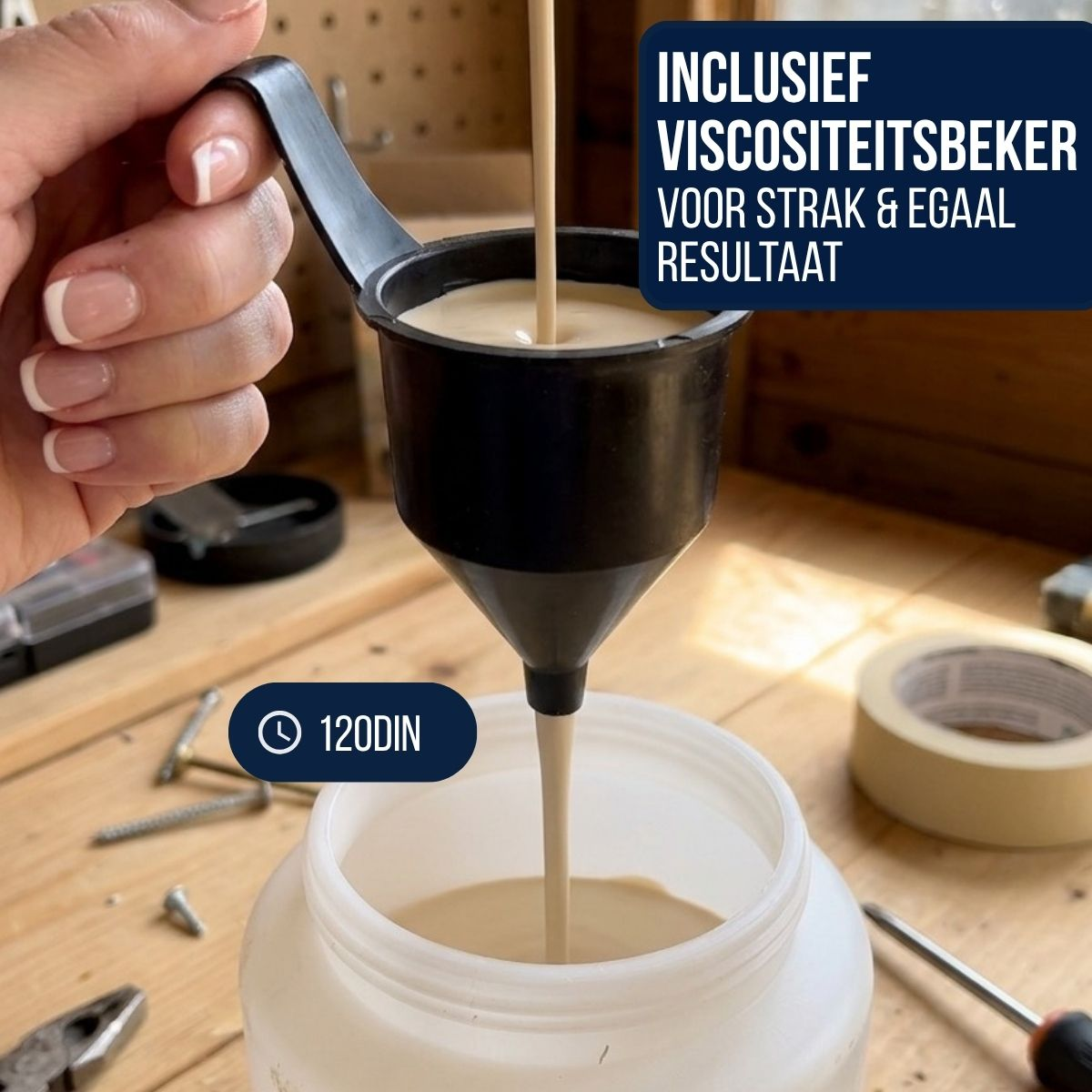 A hand holds a black viscosity cup, pouring beige paint into a container.