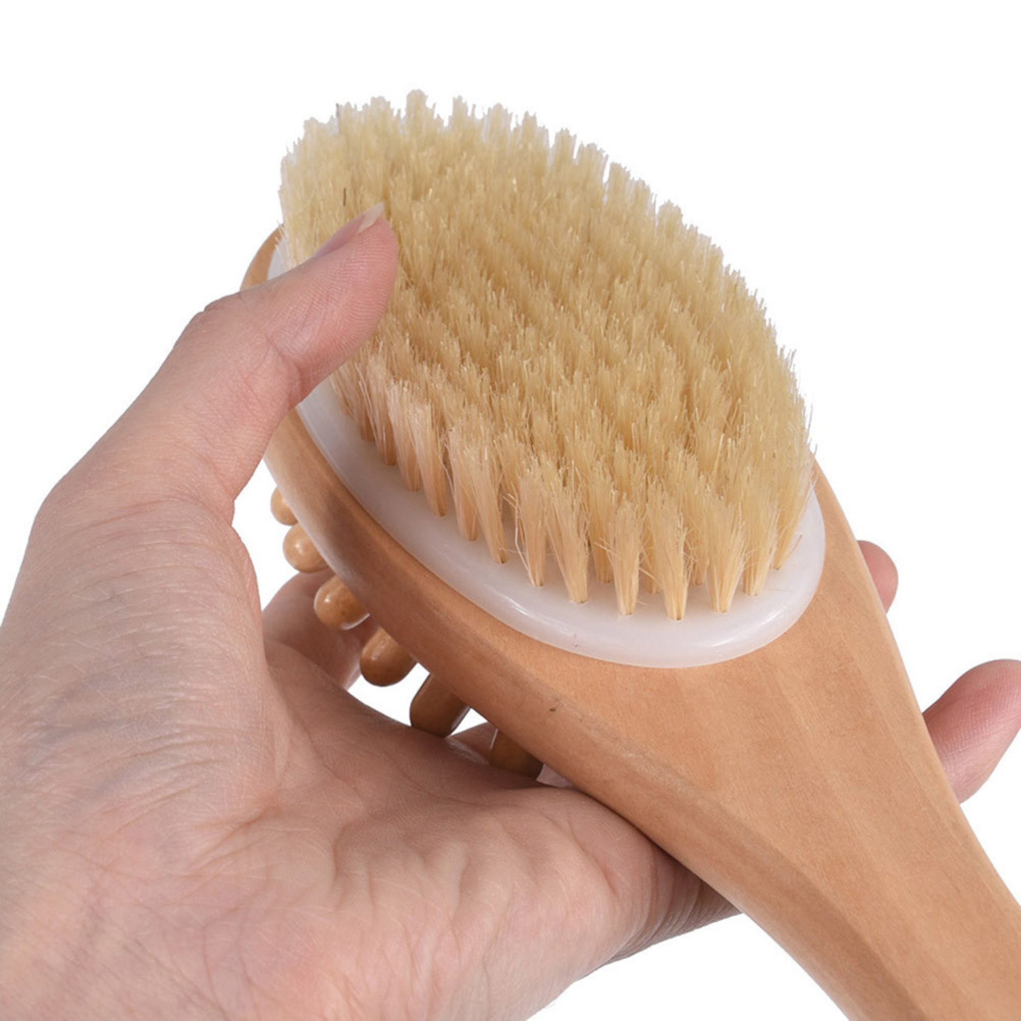 Eine Hand hält eine hölzerne Körperbürste mit hellen Borsten und Massageknöpfen auf weißem Hintergrund.