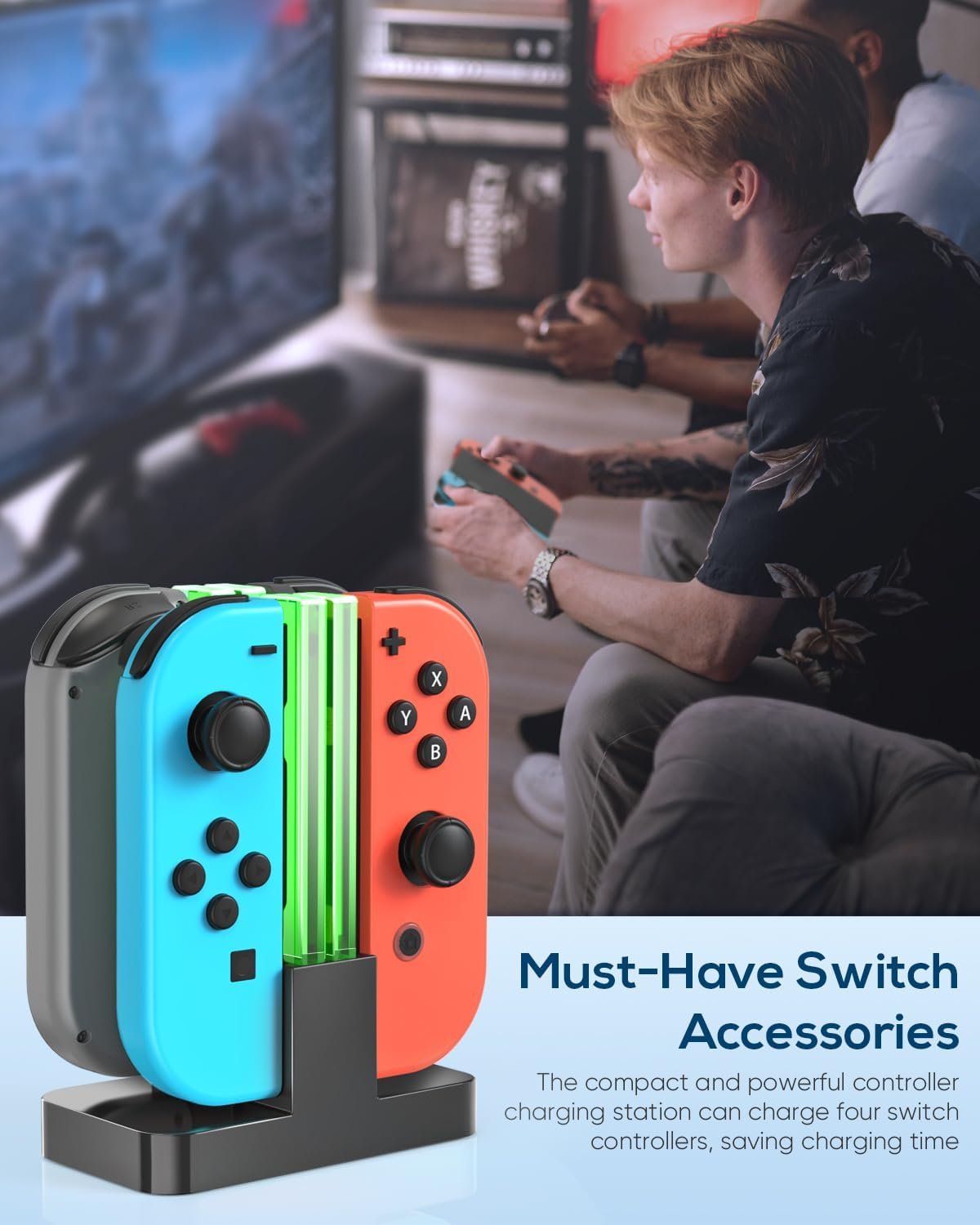 Eine Ladestation mit blauen und roten Switch-Controllern steht im Vordergrund, während Personen ein Spiel auf einem Fernseher spielen.