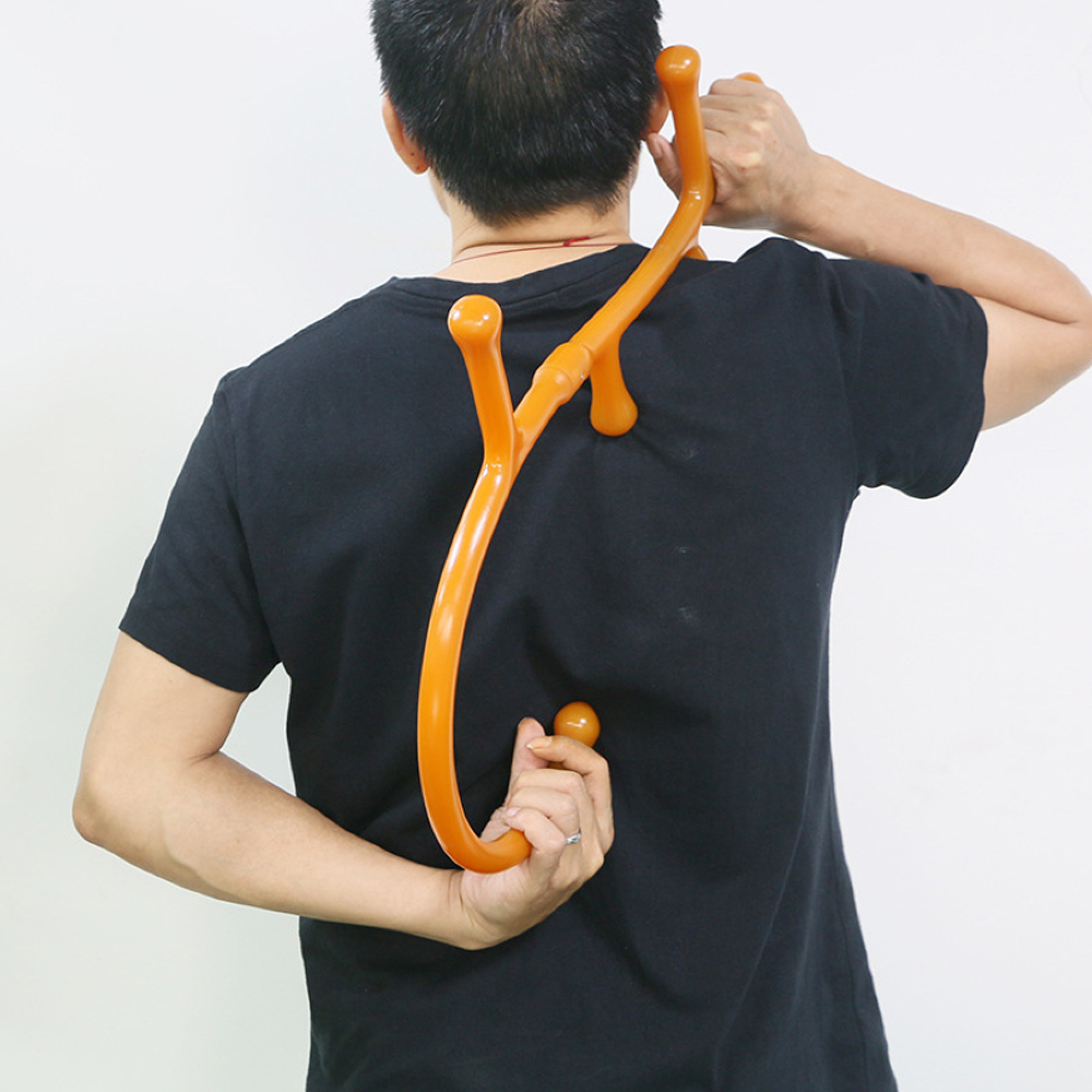 Eine Person in einem schwarzen T-Shirt benutzt einen orangefarbenen S-förmigen Rückenkratzer.