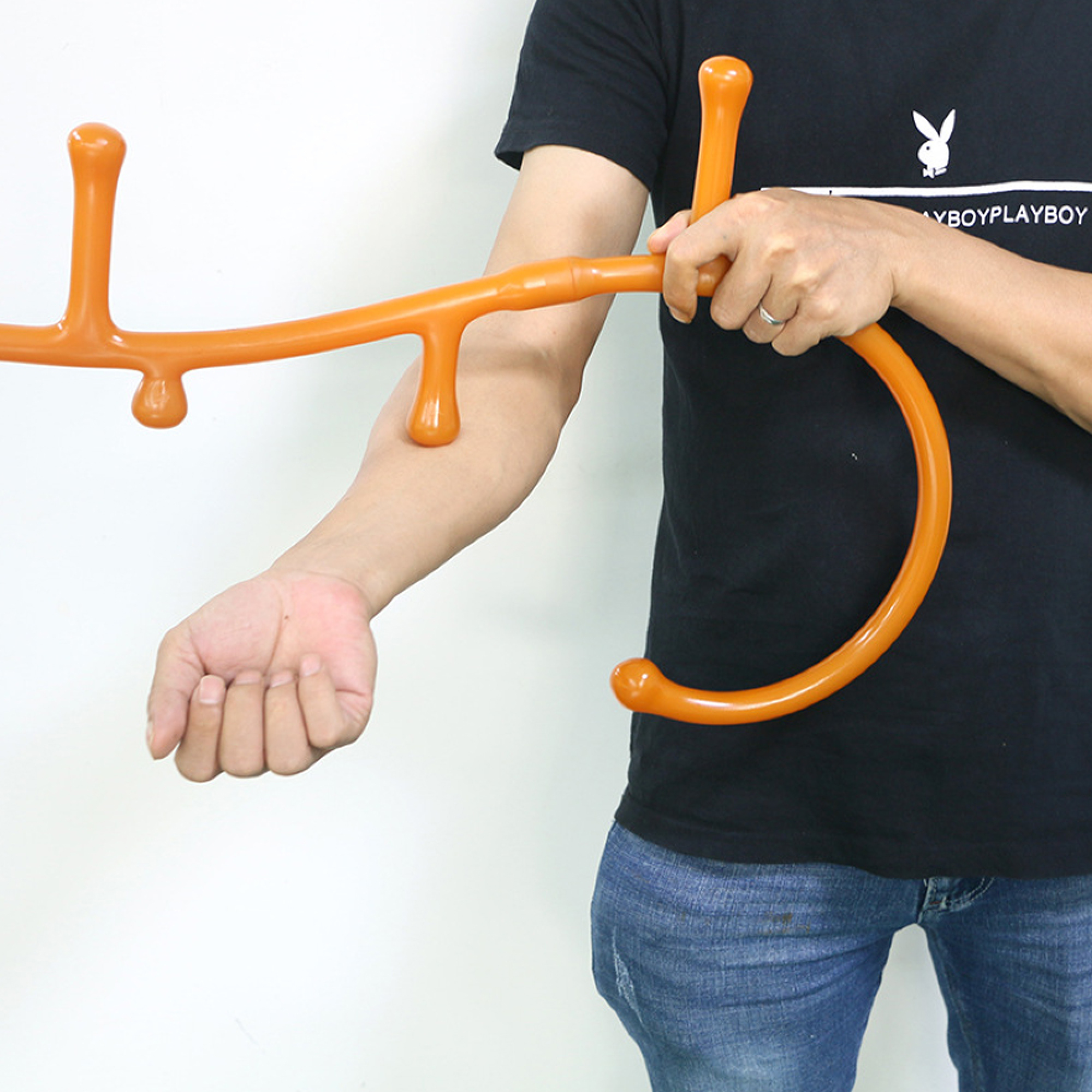 Eine Person in einem schwarzen T-Shirt hält ein oranges Massagegerät mit mehreren Knöpfen.