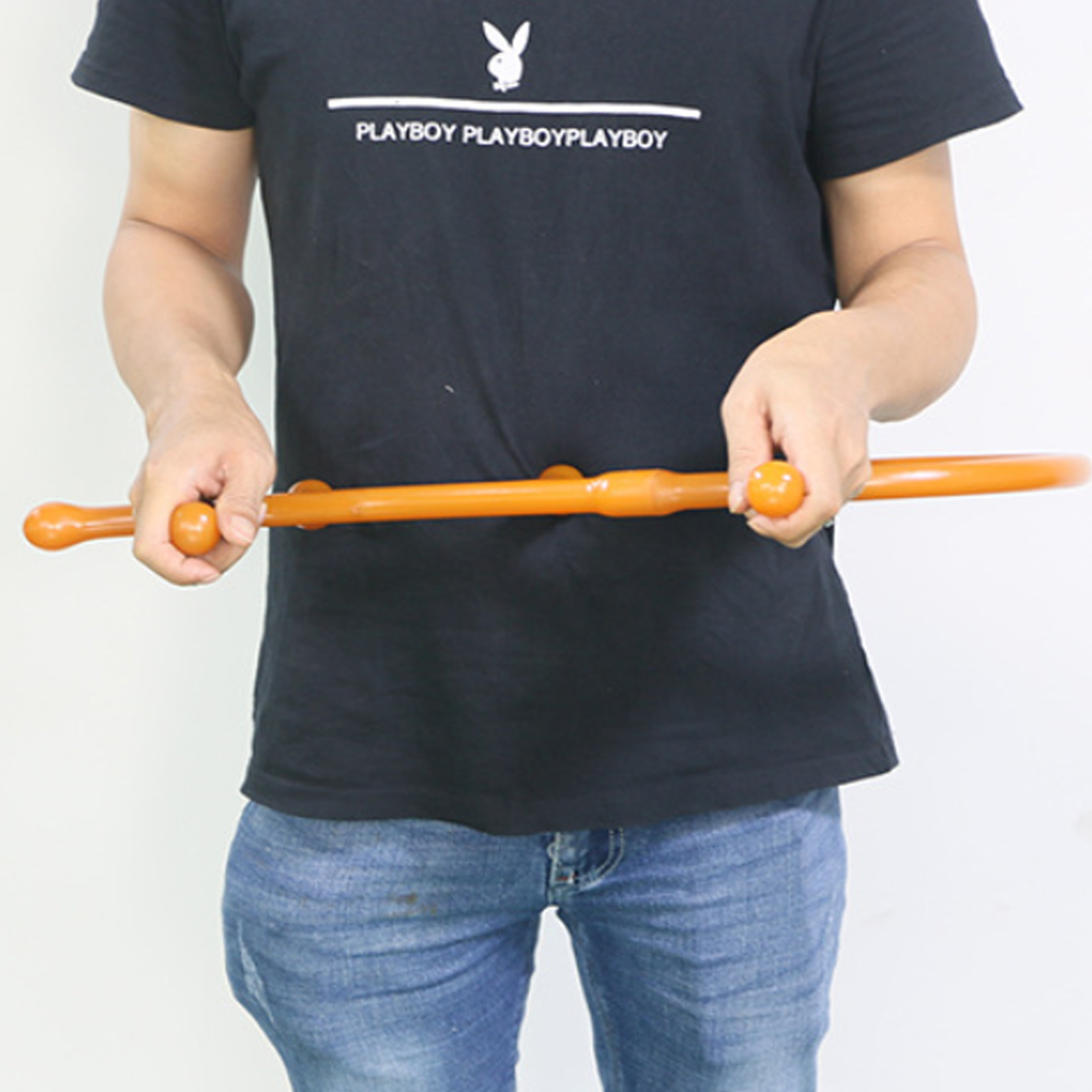 Eine Person im schwarzen T-Shirt und Jeans hält ein orangenes Massagegerät mit Noppen vor sich.