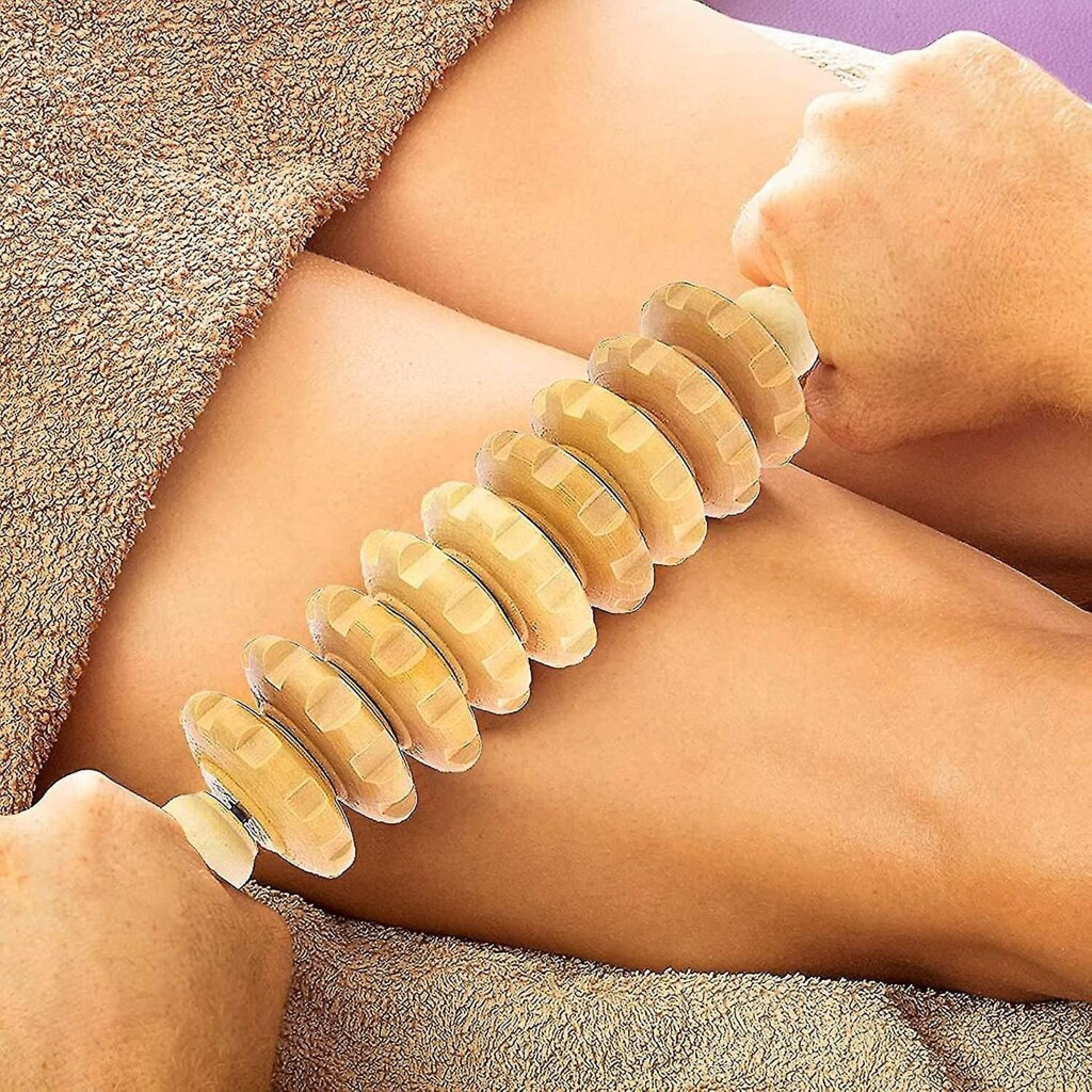 Holzmassagegerät rollt über ein Bein auf einem Handtuch.