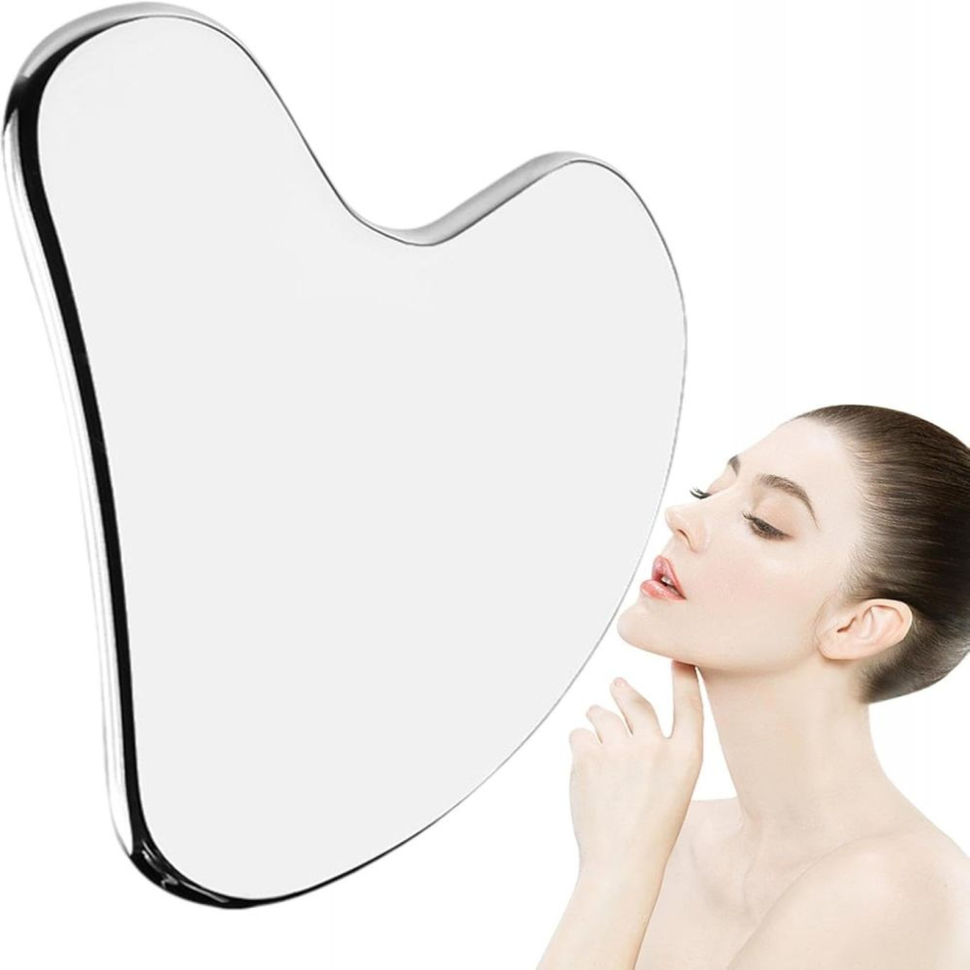 Eine Frau hält eine große, herzförmige Gua-Sha-Platte aus Stein an ihr Gesicht.