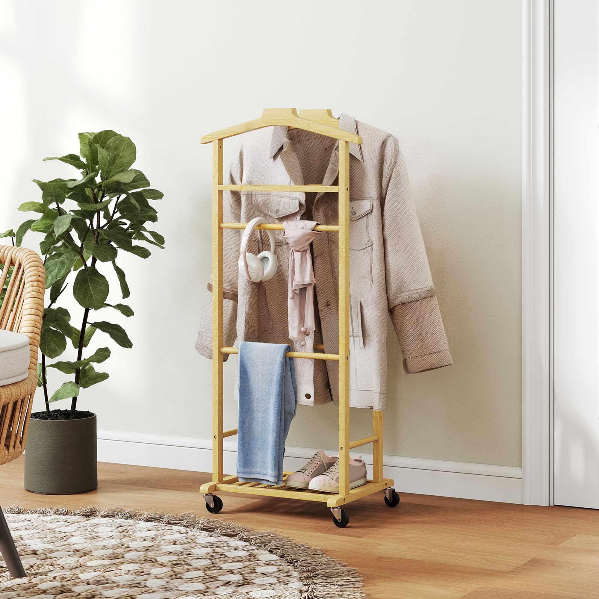 Un galán de noche de madera con ruedas sostiene una chaqueta, bufanda, auriculares, jeans y zapatillas, con una planta.