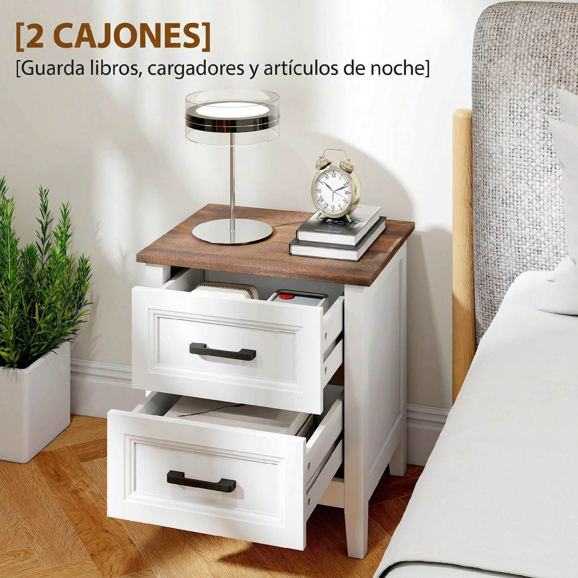 Mesita de noche blanca con tapa de madera, dos cajones abiertos, lámpara, reloj y libros al lado de una cama.