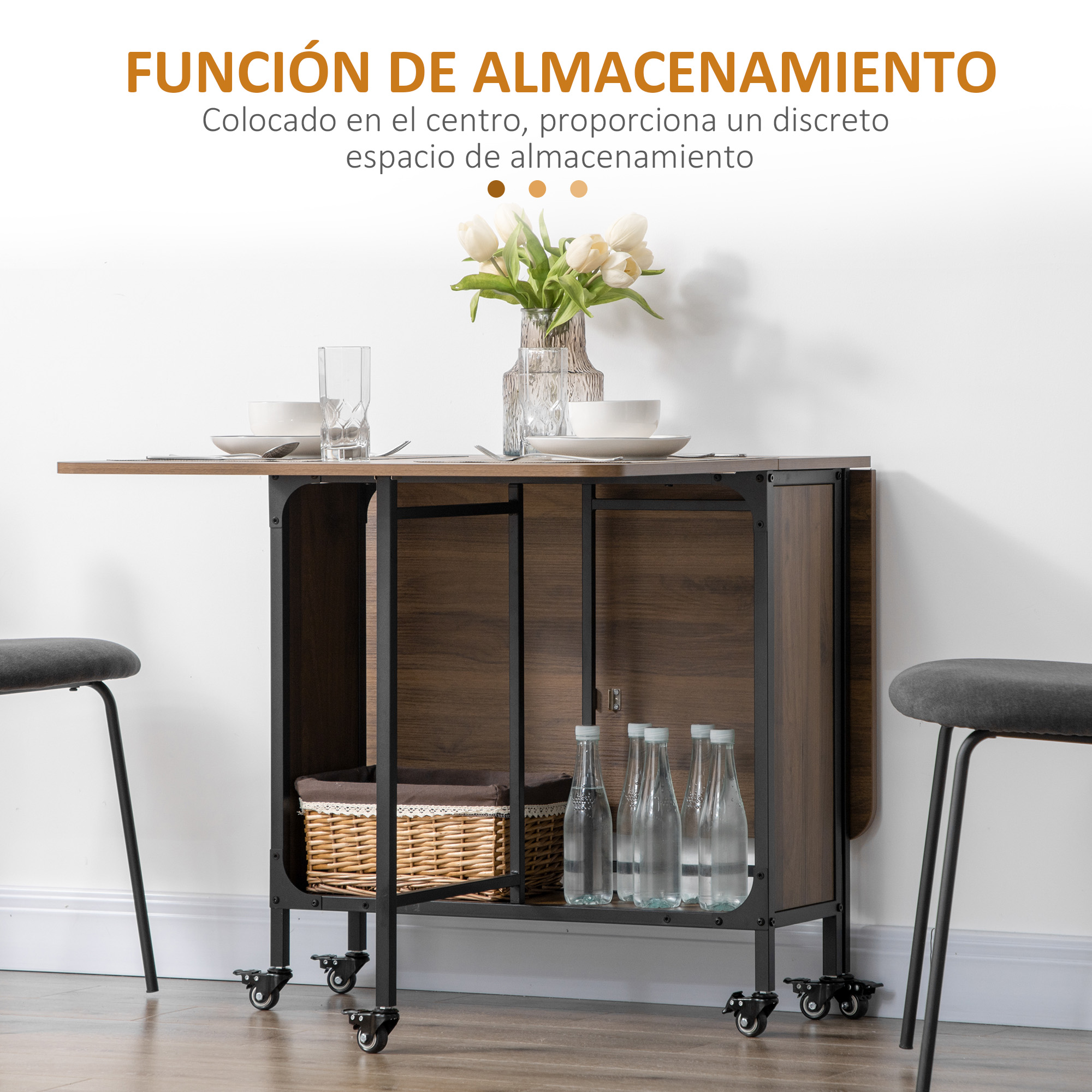 Carro de cocina de madera plegable con estantes, botellas, cesta y dos taburetes grises contra una pared blanca.